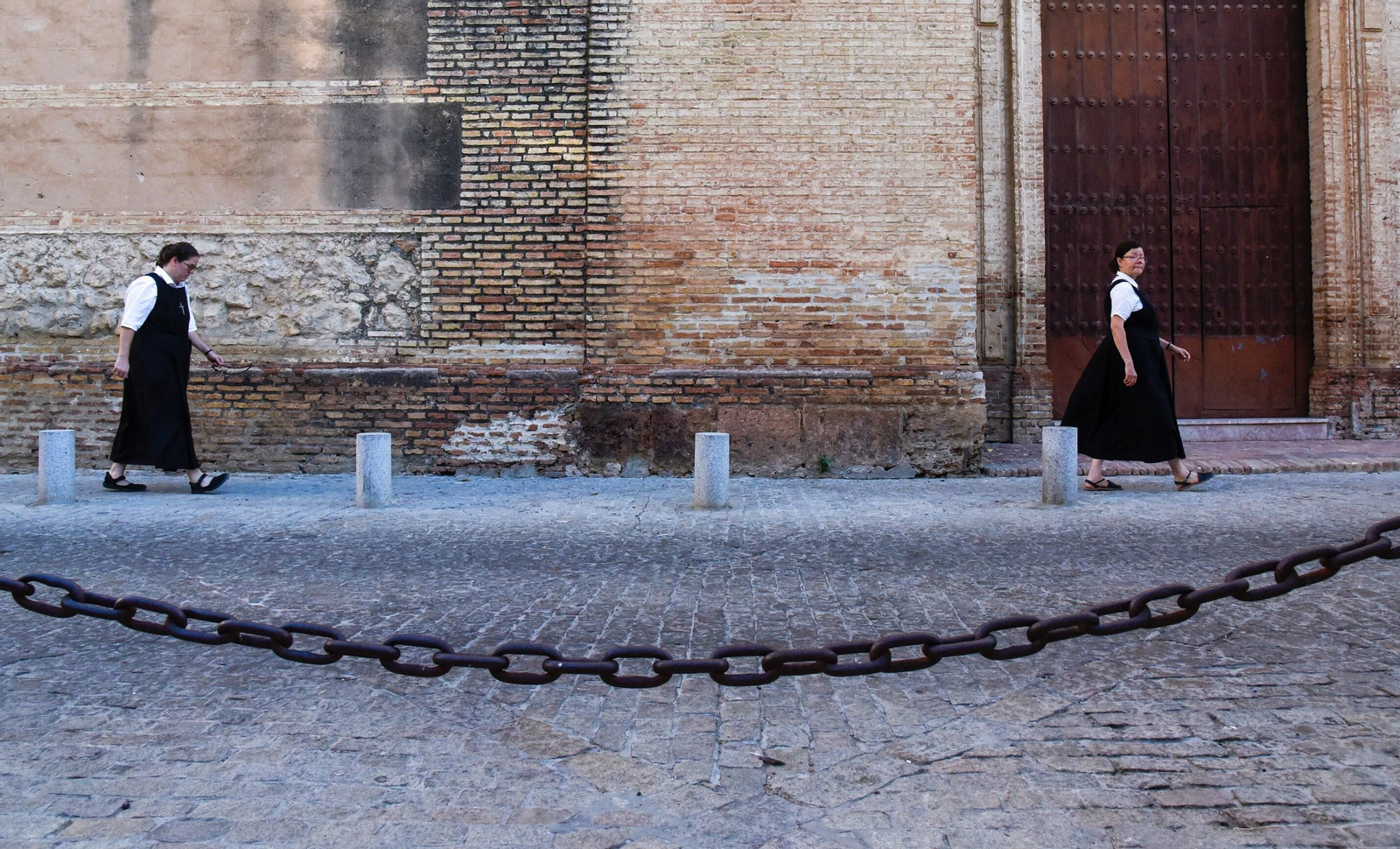 Dos religiosas de las HAM pasan ante el convento de las Descalzas de Carmona.