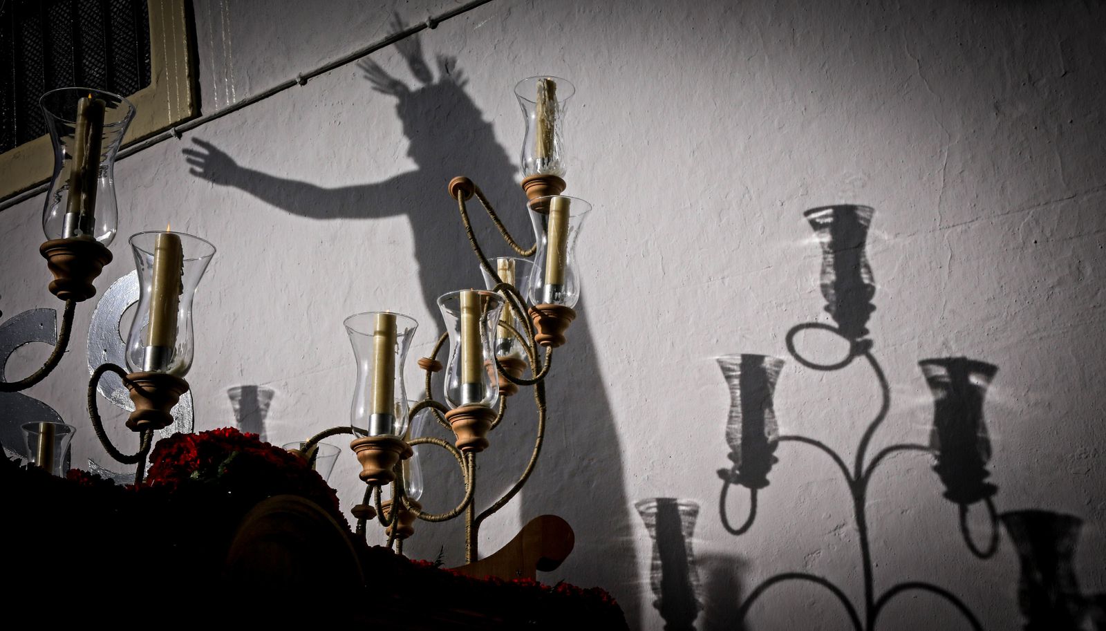 Los candelabros del Resucitado, con la proyección de la sombra de la talla detrás.