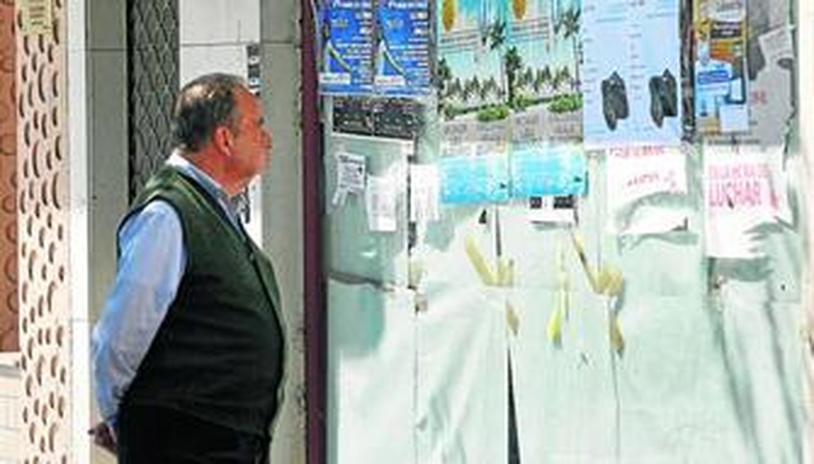 Un viandante observa los carteles que tapan el escaparate de la oficina cerrada de Viajes Marsans en el paseo de Canalejas, en Cádiz.