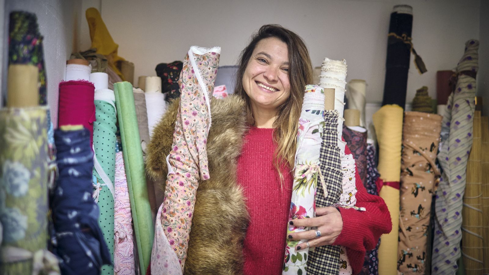 Floren, en su local, rodeada de rollos de tela.