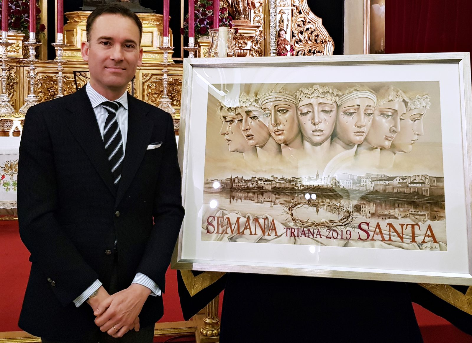 Sergio Cornejo junto al cartel de la Semana Santa de Triana diseñado por él en 2019.