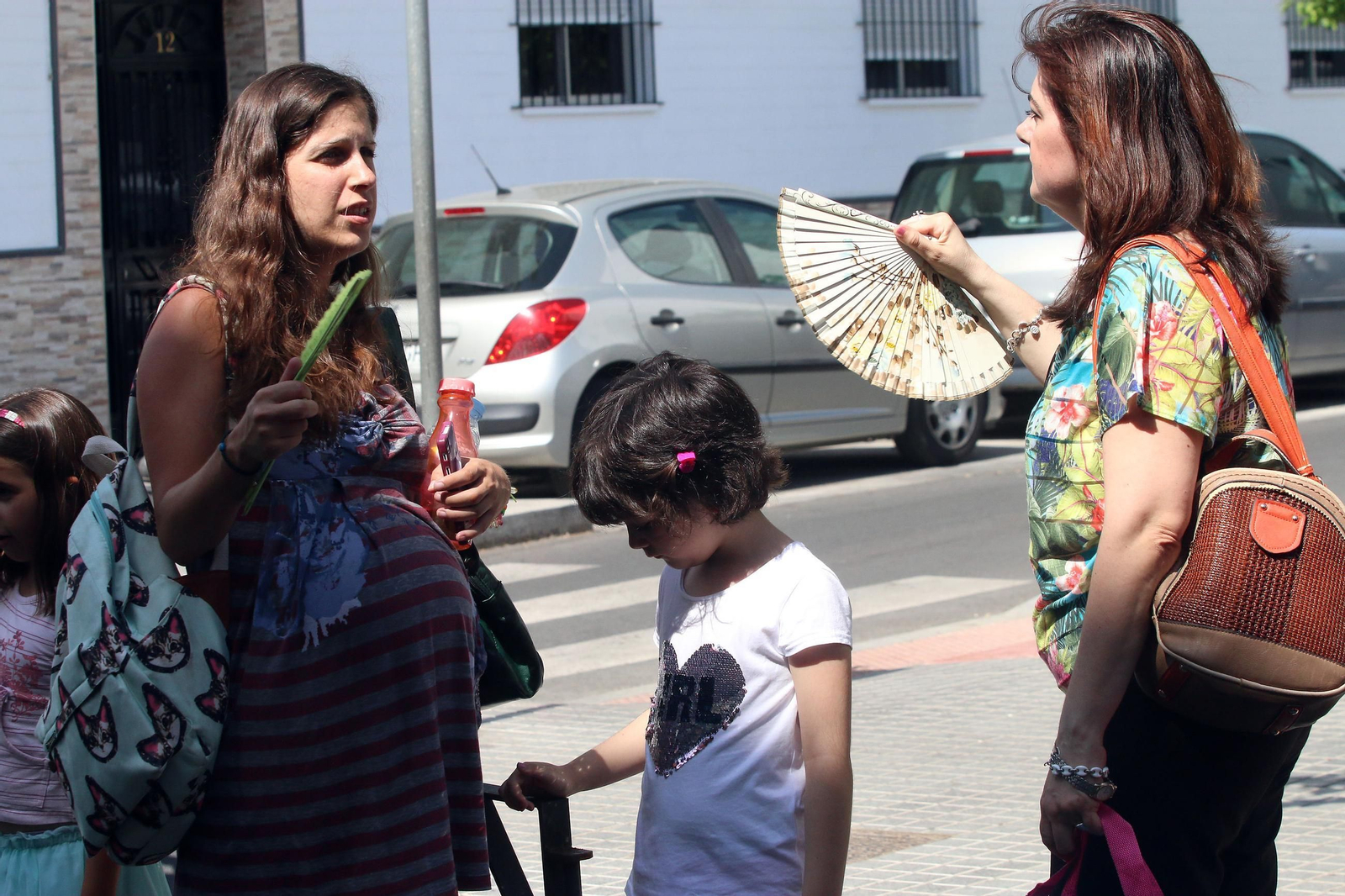 Dos madres se abanican mientras recogen a sus hijos del colegio. Dos madres se abanican mientras recogen a sus hijos del colegio.