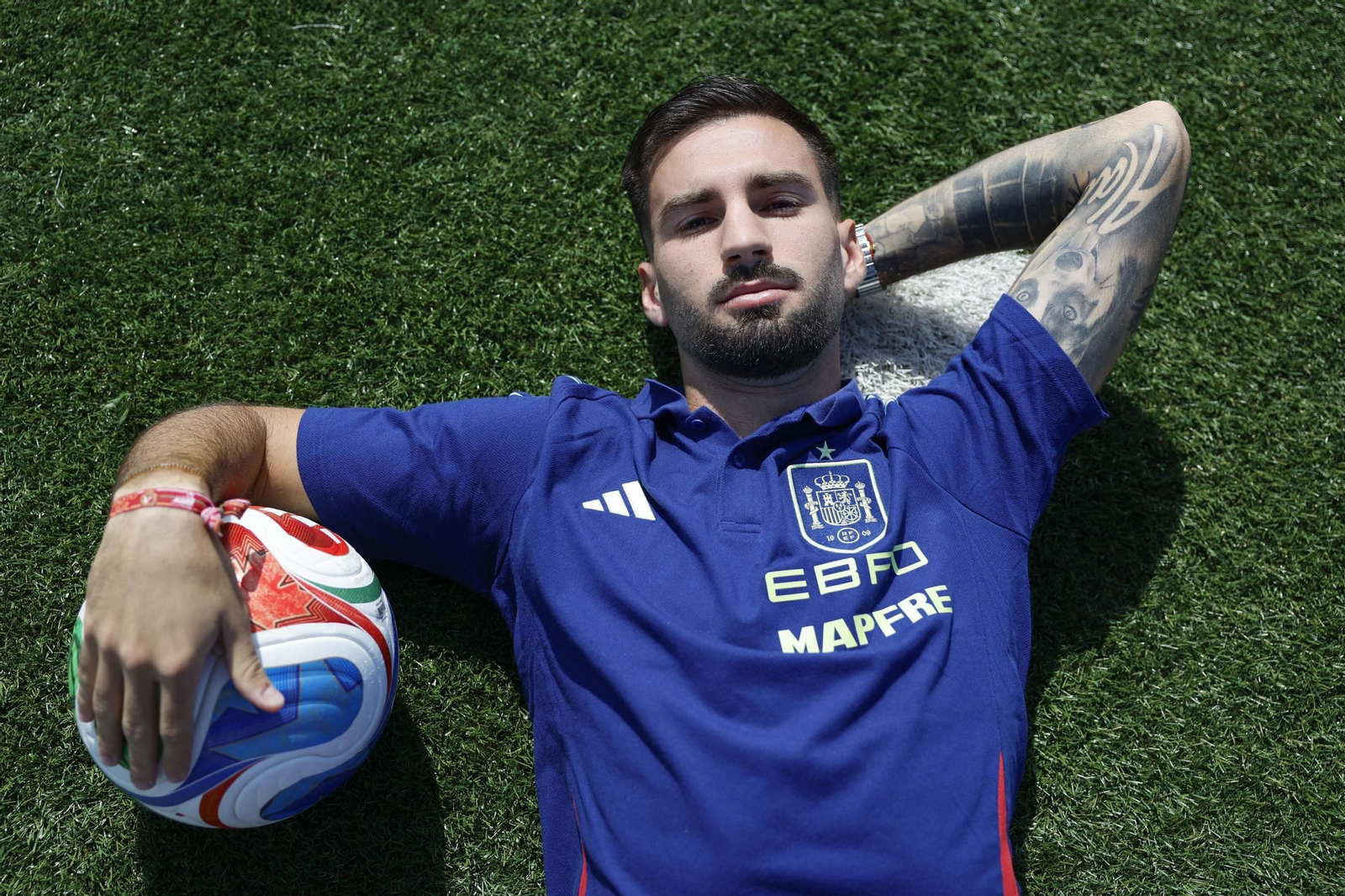 Álex Baena tendido sobre la hierba de uno de los campos de la Ciudad del Fútbol de Las Rozas durante la entrevista.