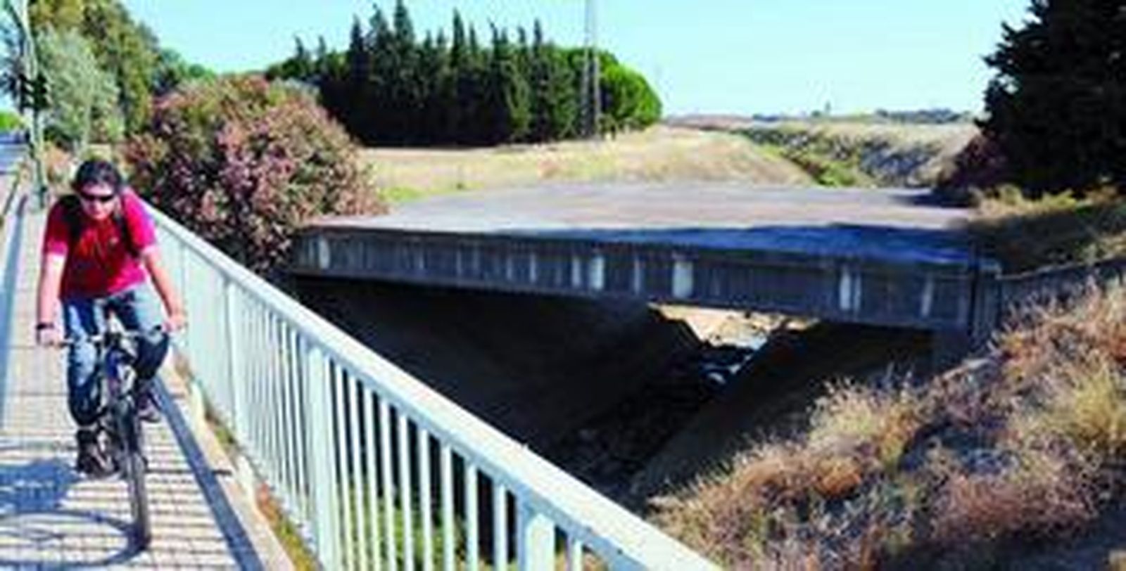 Un ciclista atraviesa por uno de los pasos elevados que salva el canal de Ranillas, en Sevilla Este.