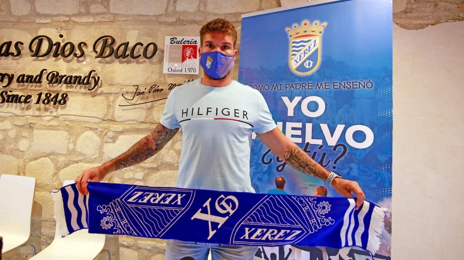 Lolo Garrido posa con la bufanda del Xerez CD tras ser presentado en Bodegas Dios Baco.