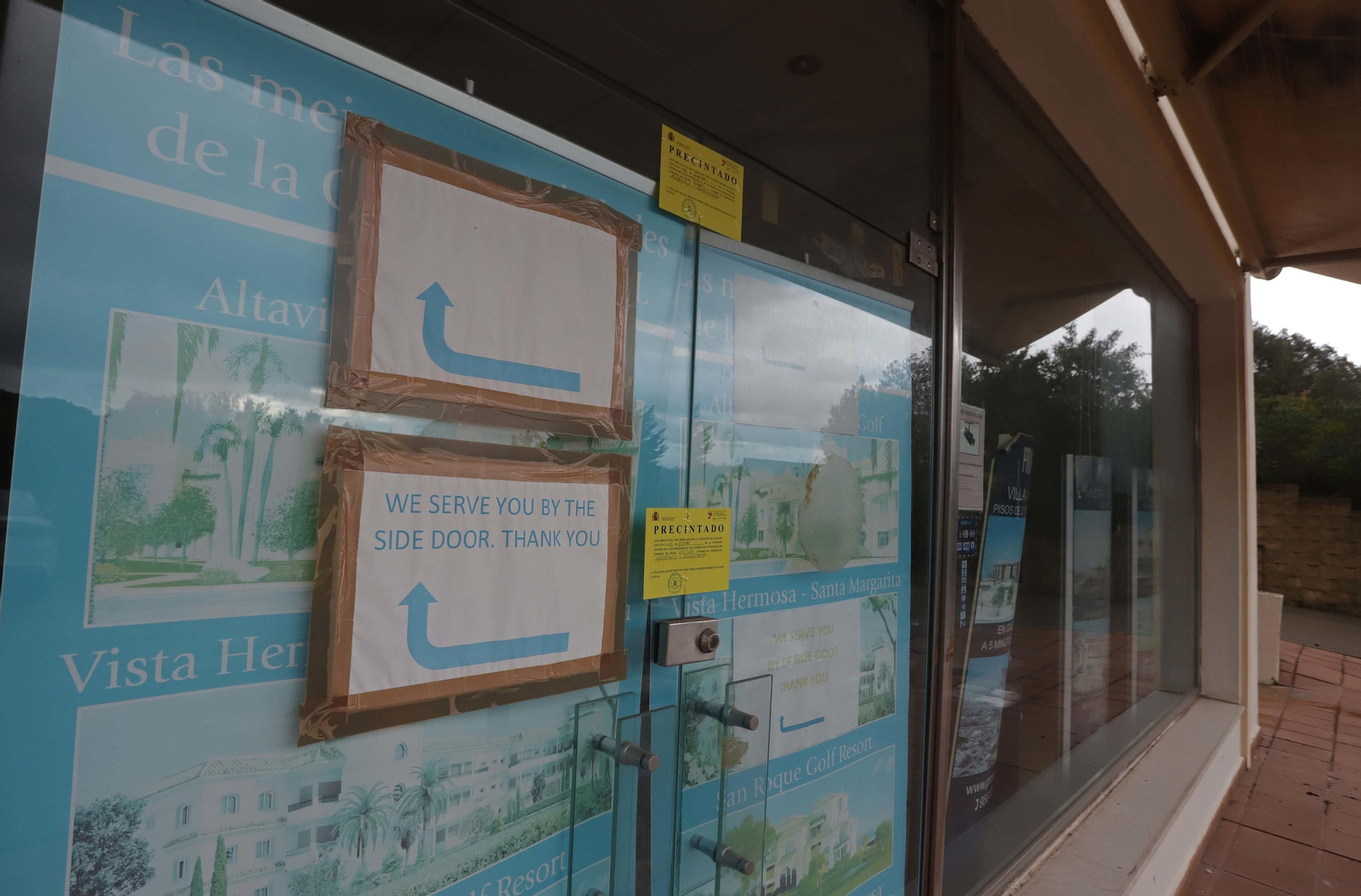 La puerta de la oficina de Promaga está precintada, aunque un cartel en inglés informa de que se atiende por la puerta trasera.