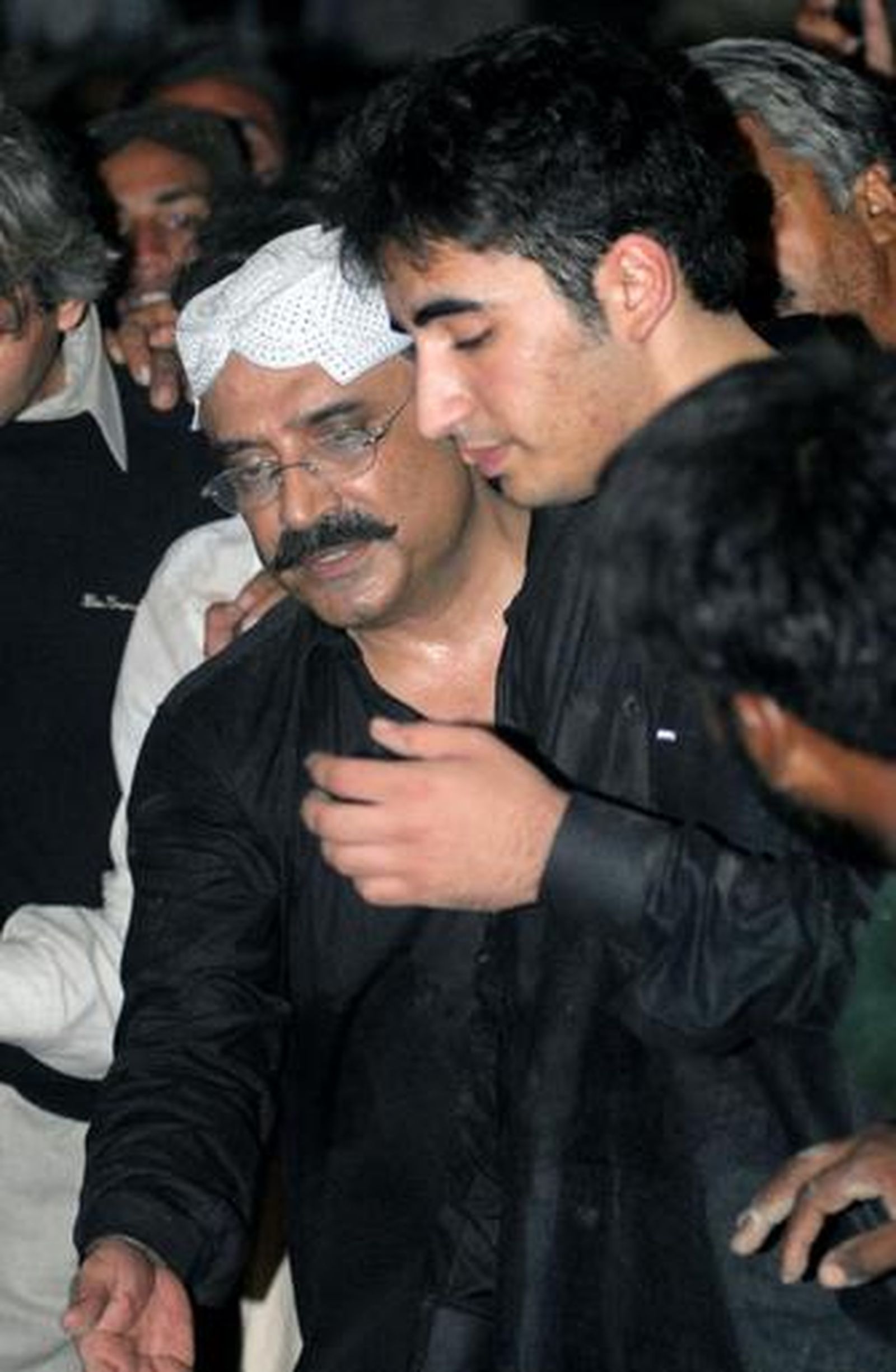 El marido de Bhutto consuela a uno de sus hijos tras el funeral.