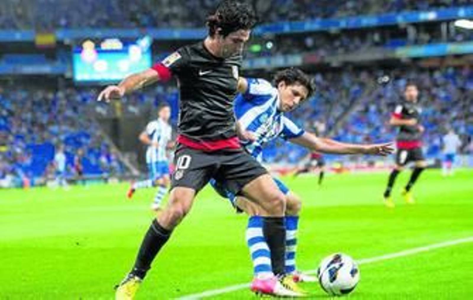 El turco Arda Turan protege el balón ante la presión del lateral Javi López.