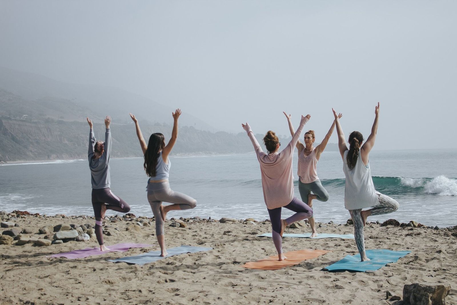 Un grupo de mujeres hace yoga en la playa.