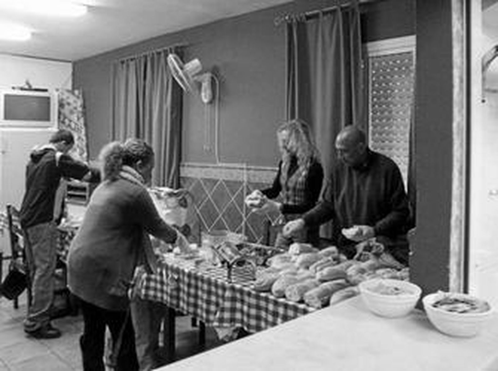 Usuarios y trabajadores del Centro de Encuentro y Acogida preparan bocadillos.