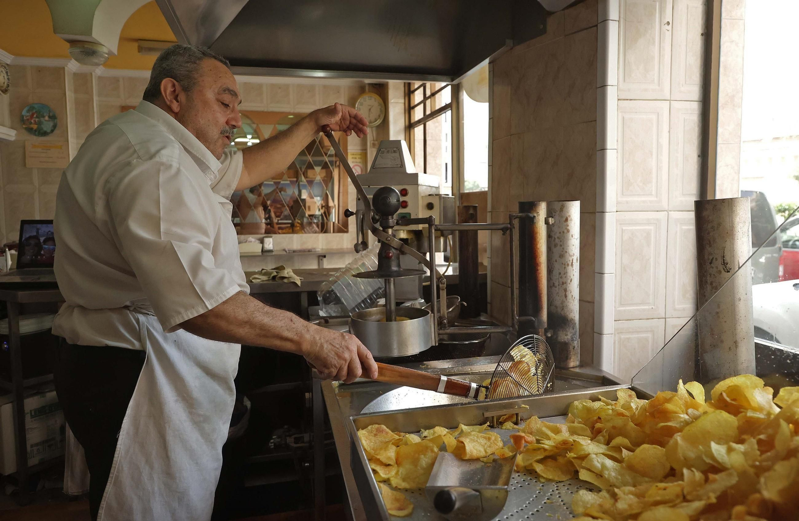 Carlos Gómez rellena el expositor de patatas fritas de 'La Oriental', en Algeciras.