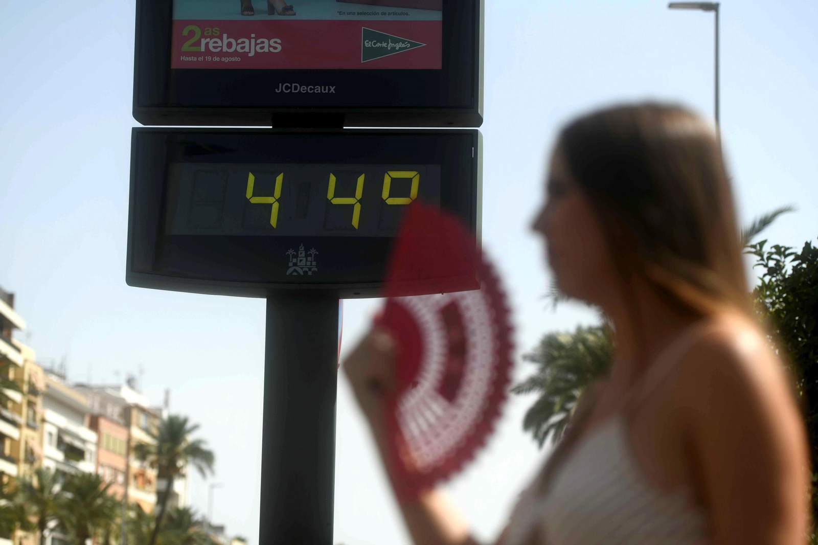 Una joven se abanica delante de un termómetro que marca 44 grados.