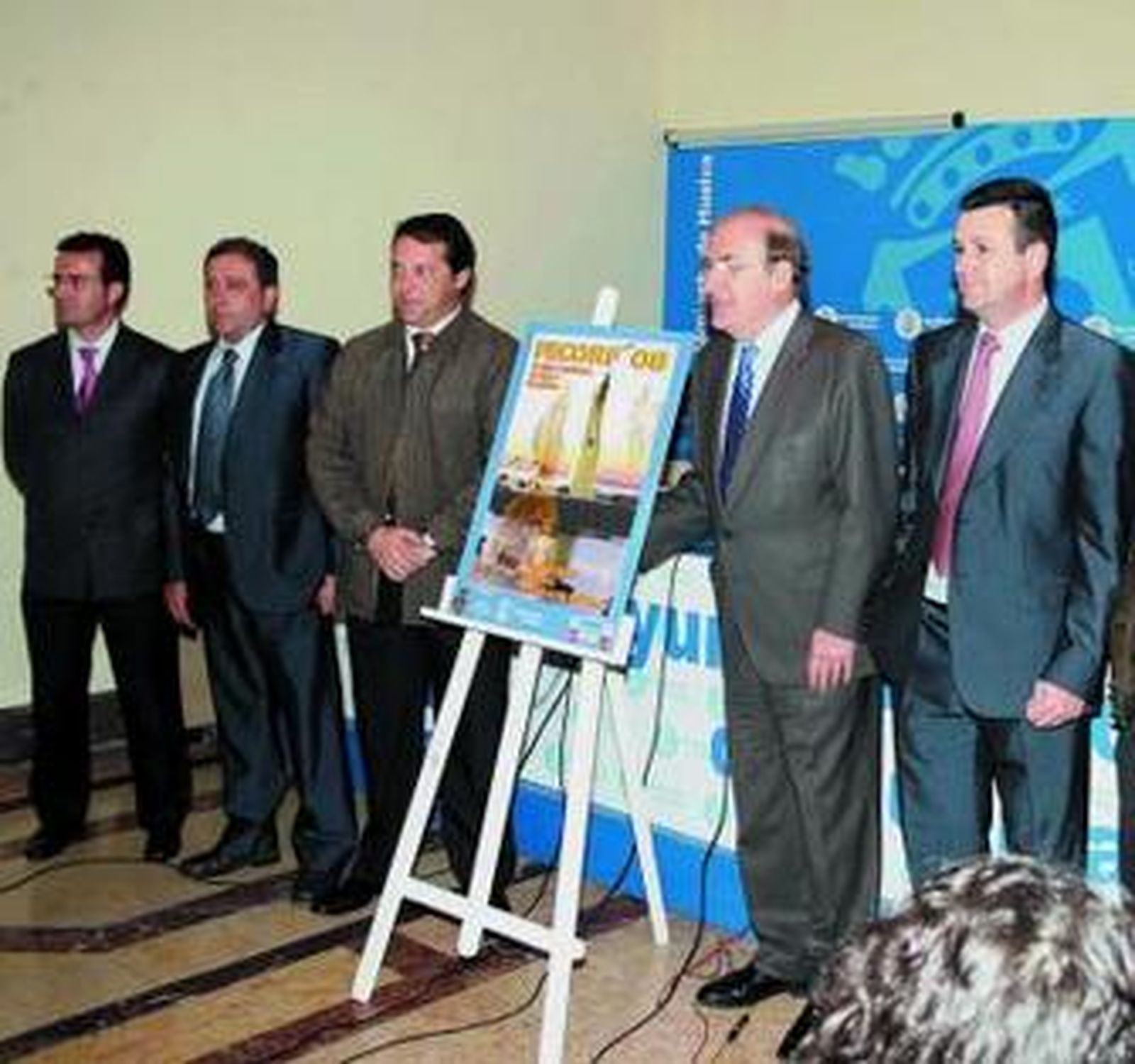 El alcalde, el presidente de Emigrantes y los patrocinadores con el cartel.