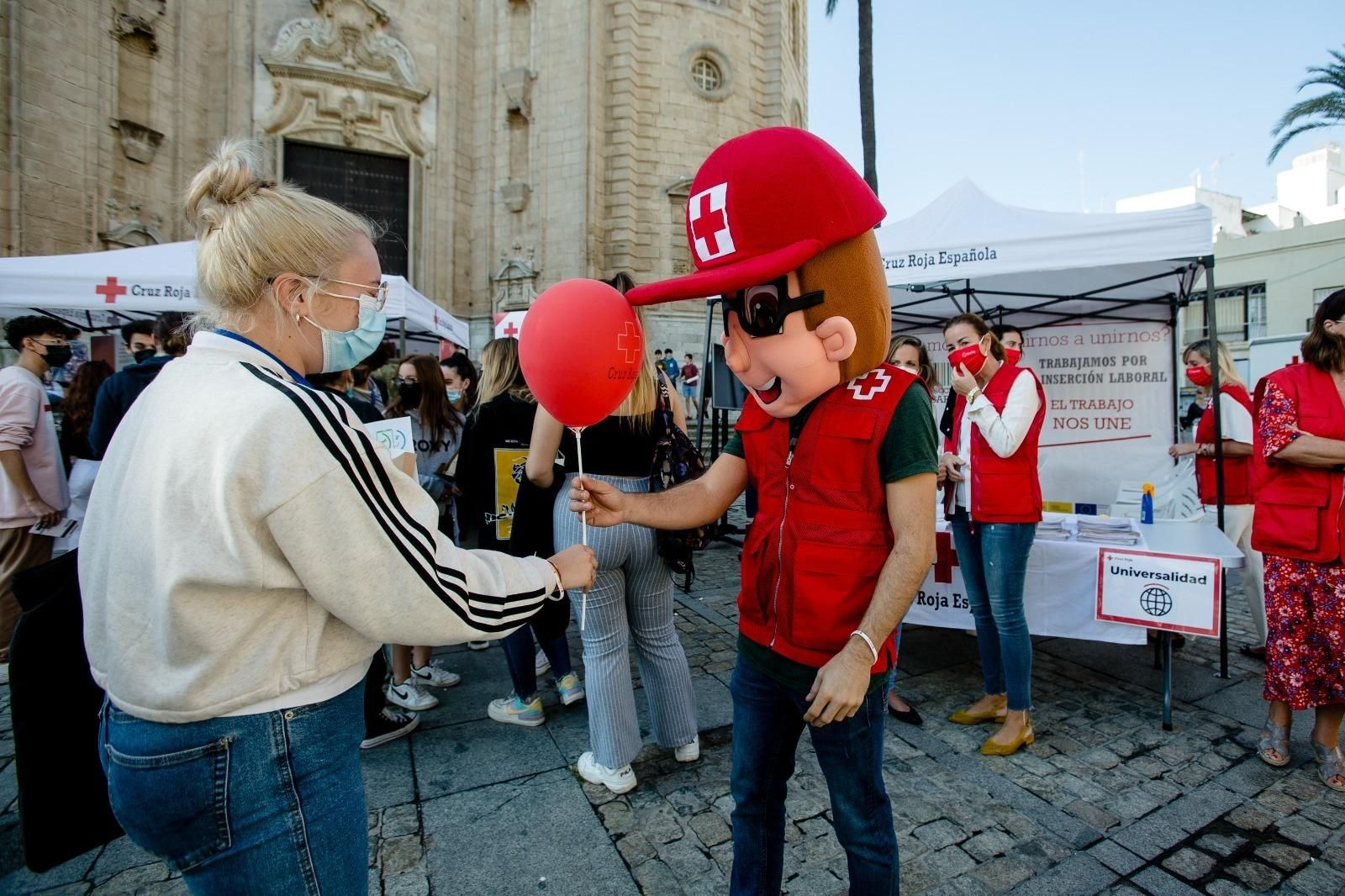 Un voluntario de Cruz Roja entrega un globo a una ciudadana.
