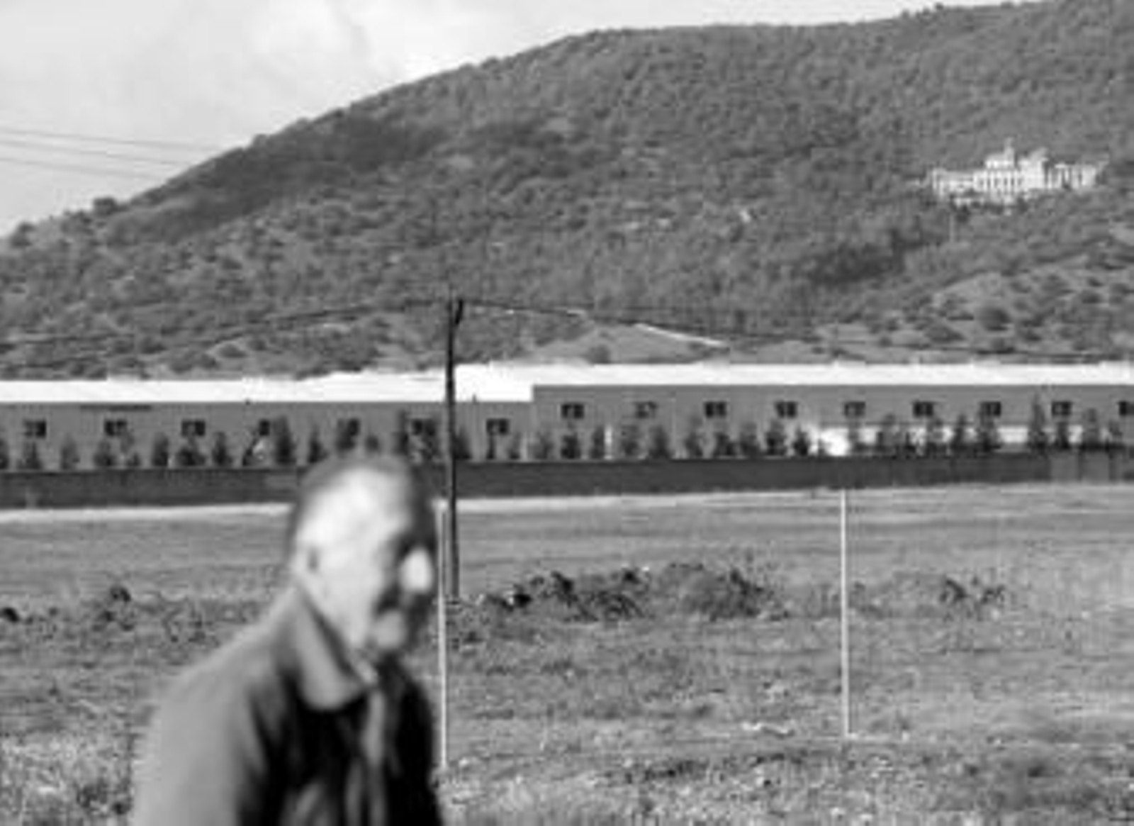 Un hombre pasa por un margen de la carretera de Palma, con las naves de Colecor y San Jerónimo al fondo.