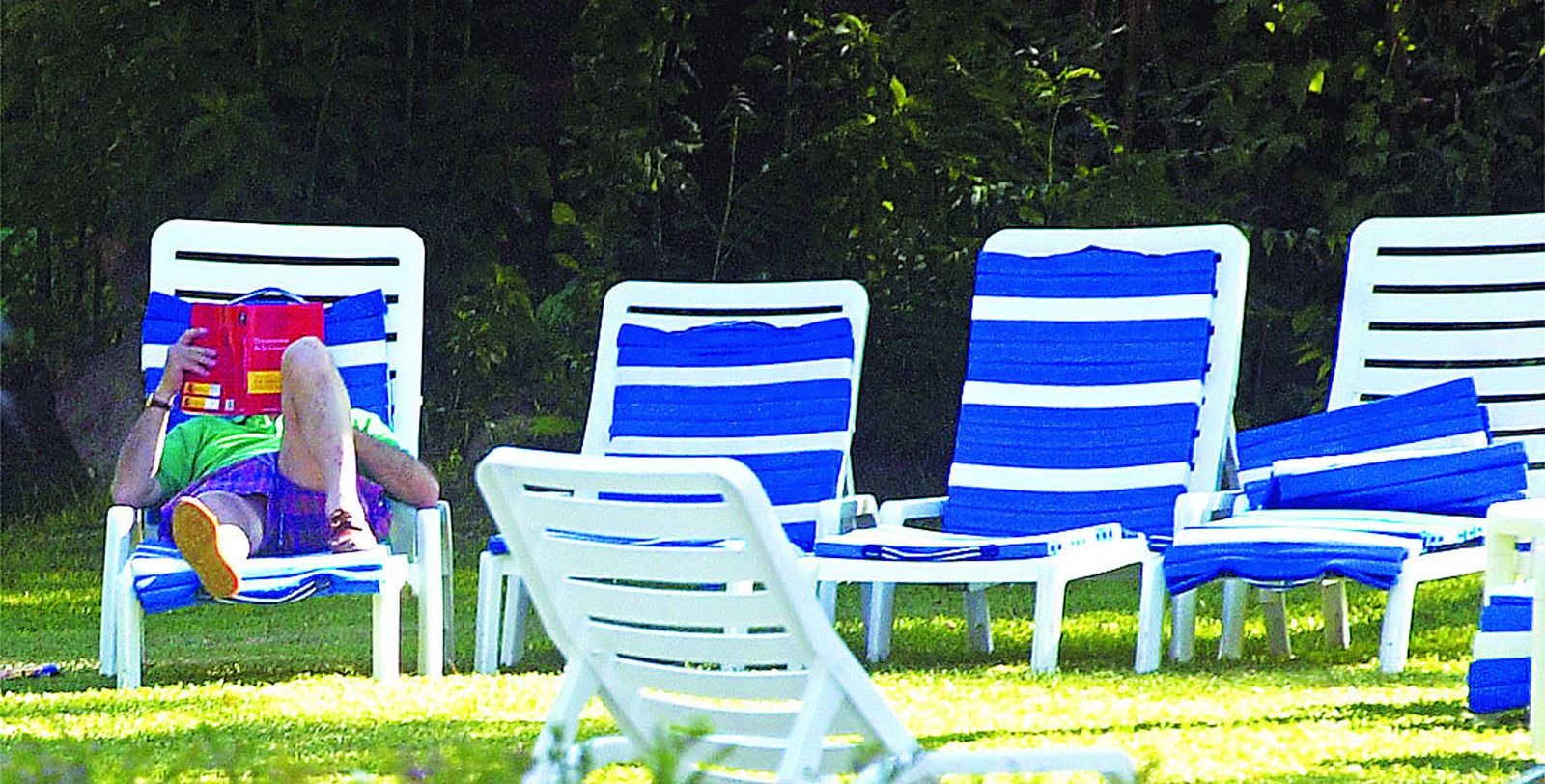 Un turista lee junto a la piscina de un hotel de Jerez.