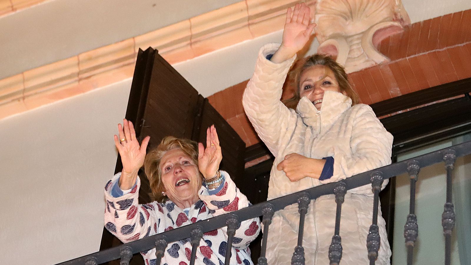 Dos mujeres saludan emocionadas al paso del cortejo real.