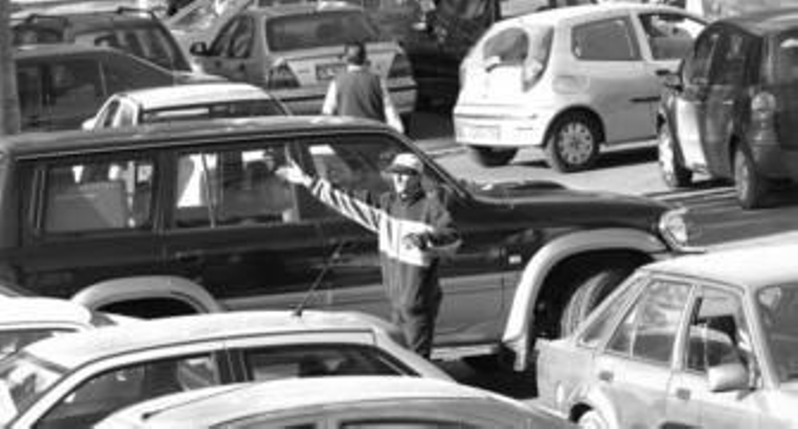 Un 'gorrilla' hace indicaciones a un conductor para estacionar un vehículo.