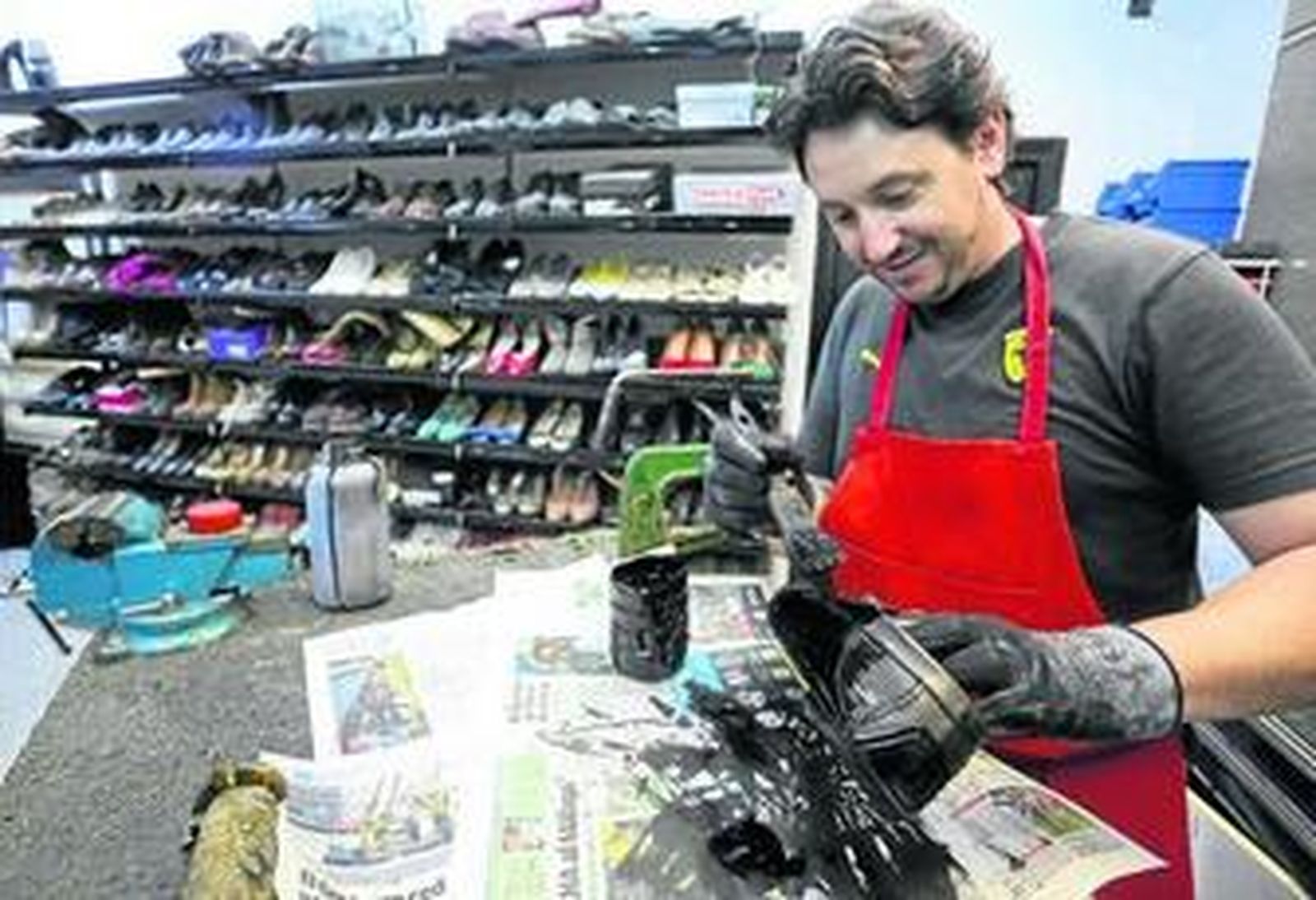 Pablo, cuyo taller lleva 30 años en El Perchel, tiñe de negro un zapato.