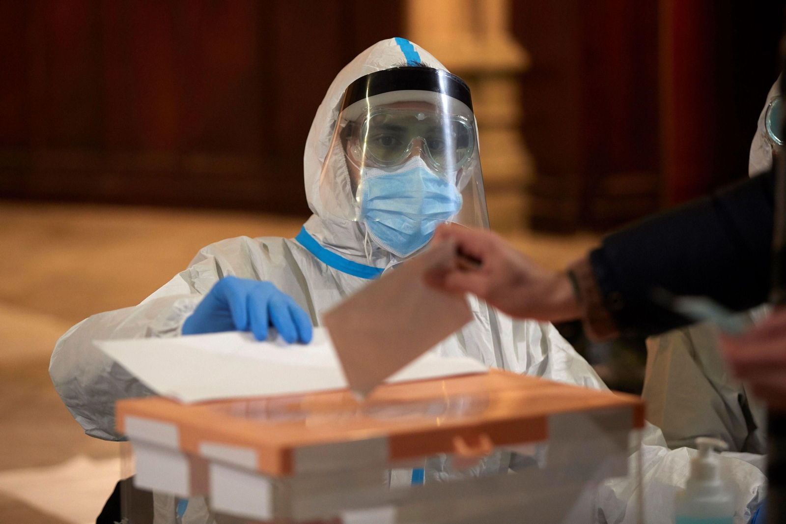 Una persona vota en la franja dedicada a las personas con Covid o con contacto en el instituto eixample, hoy domingo en Barcelona.