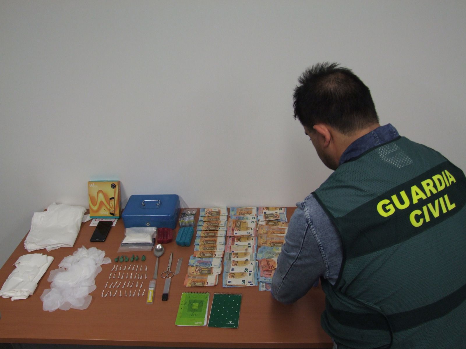 Un agente de la Benemérita custodia la droga y el dinero intervenidos.