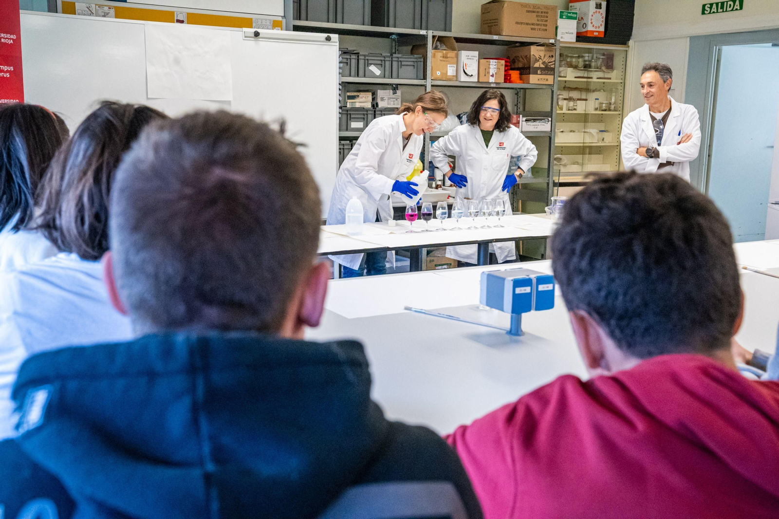 Jóvenes estudiantes asisten a una demostración científica en el interior de un aula.