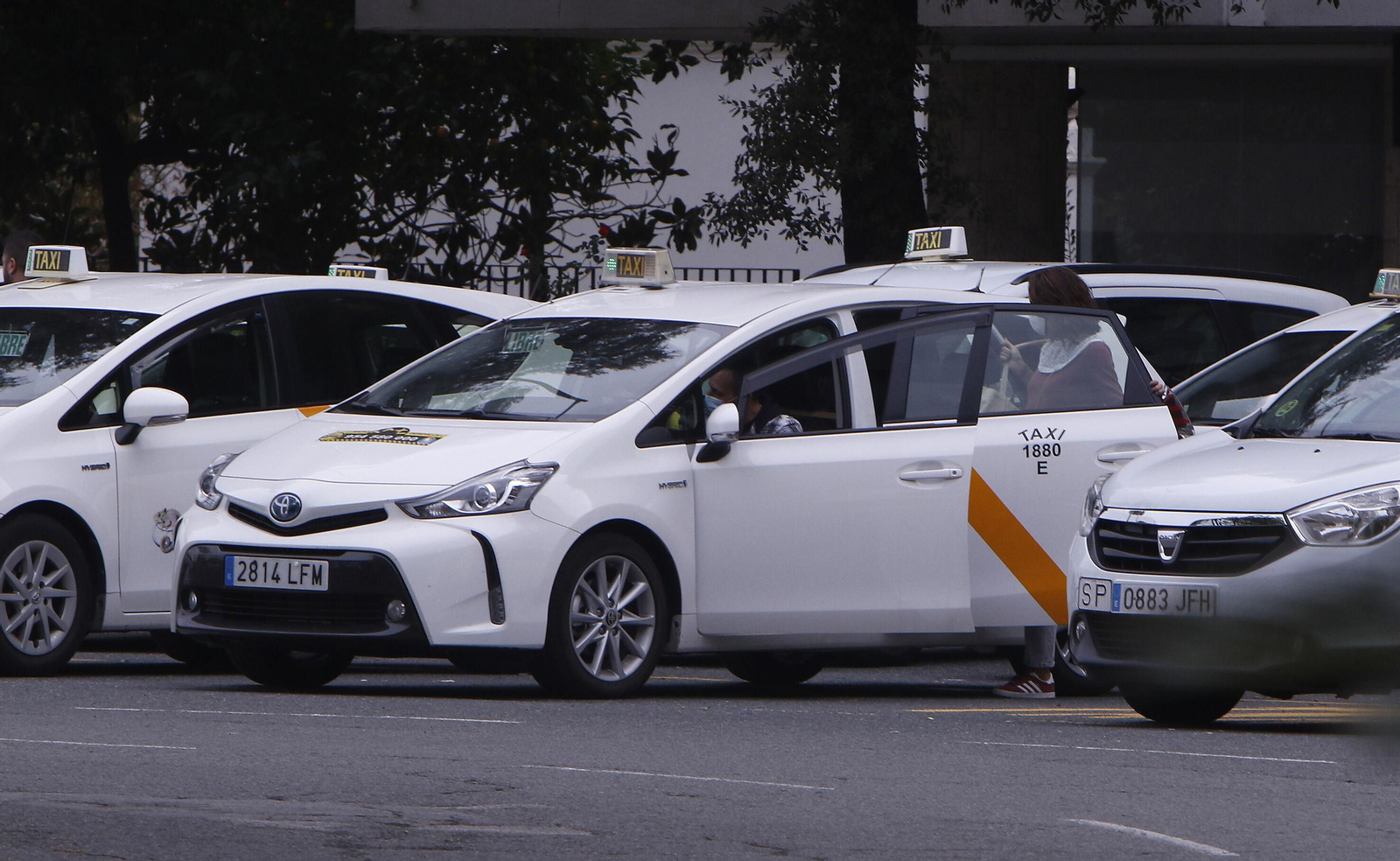 Varios taxis esperan en una parada.