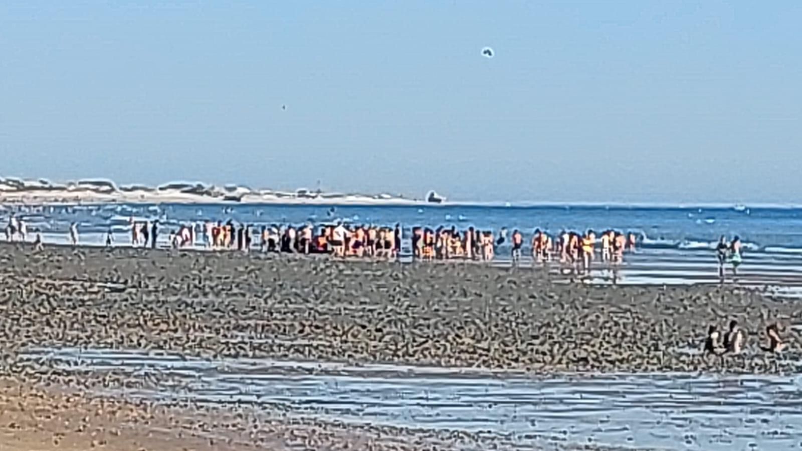 Numerosos curiosos rodean el vehículo atrapado en el fango de la playa de Camposoto