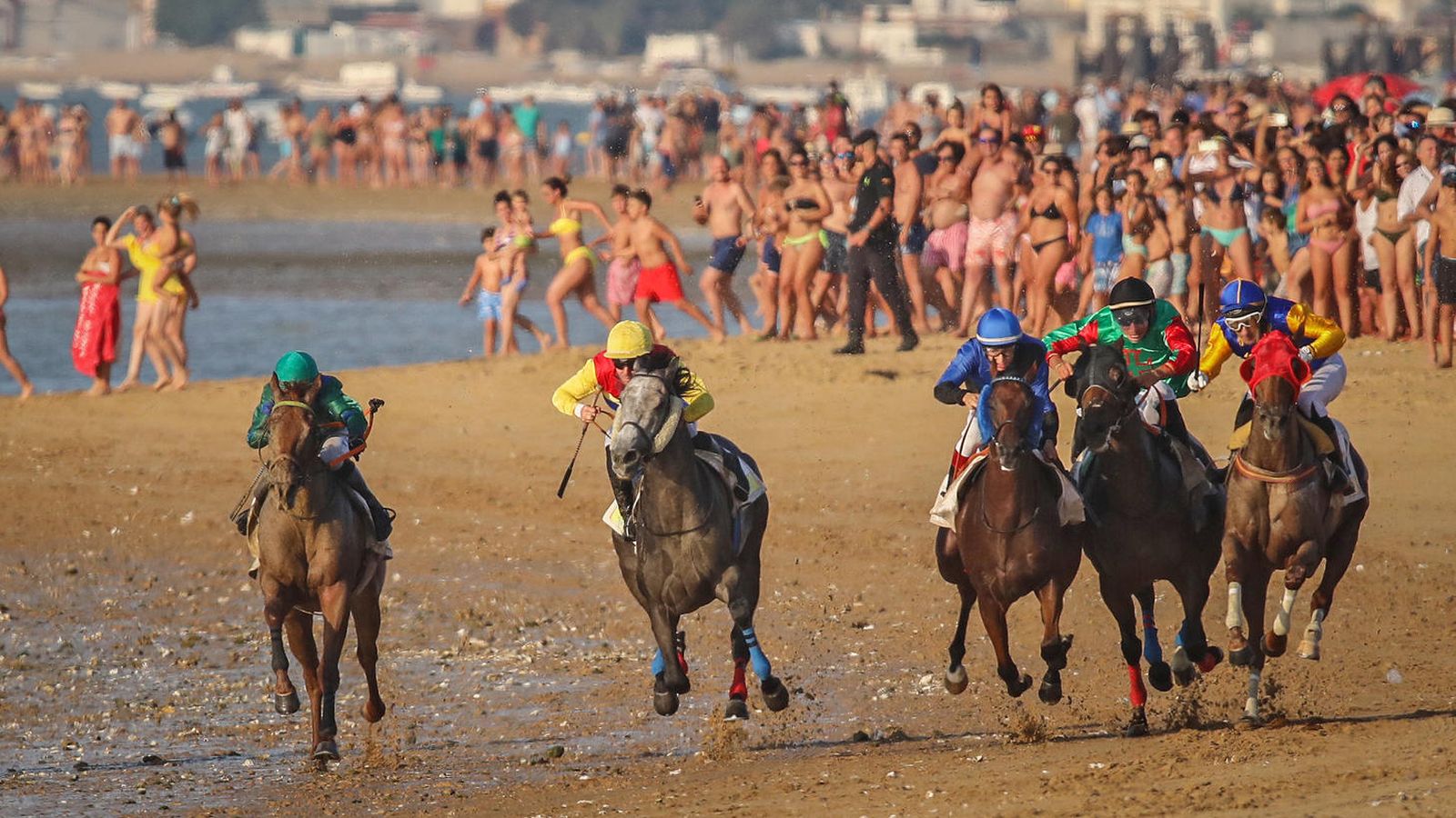 Fotografía de una carrera de caballos en la playa.