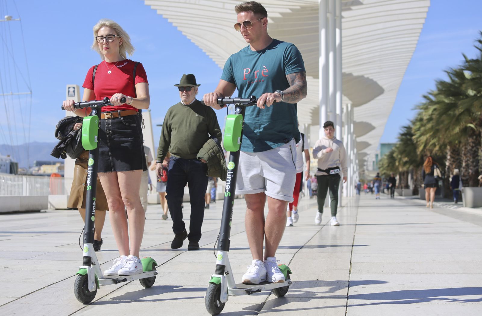 Dos personas en patinete por la zona de Muelle Uno