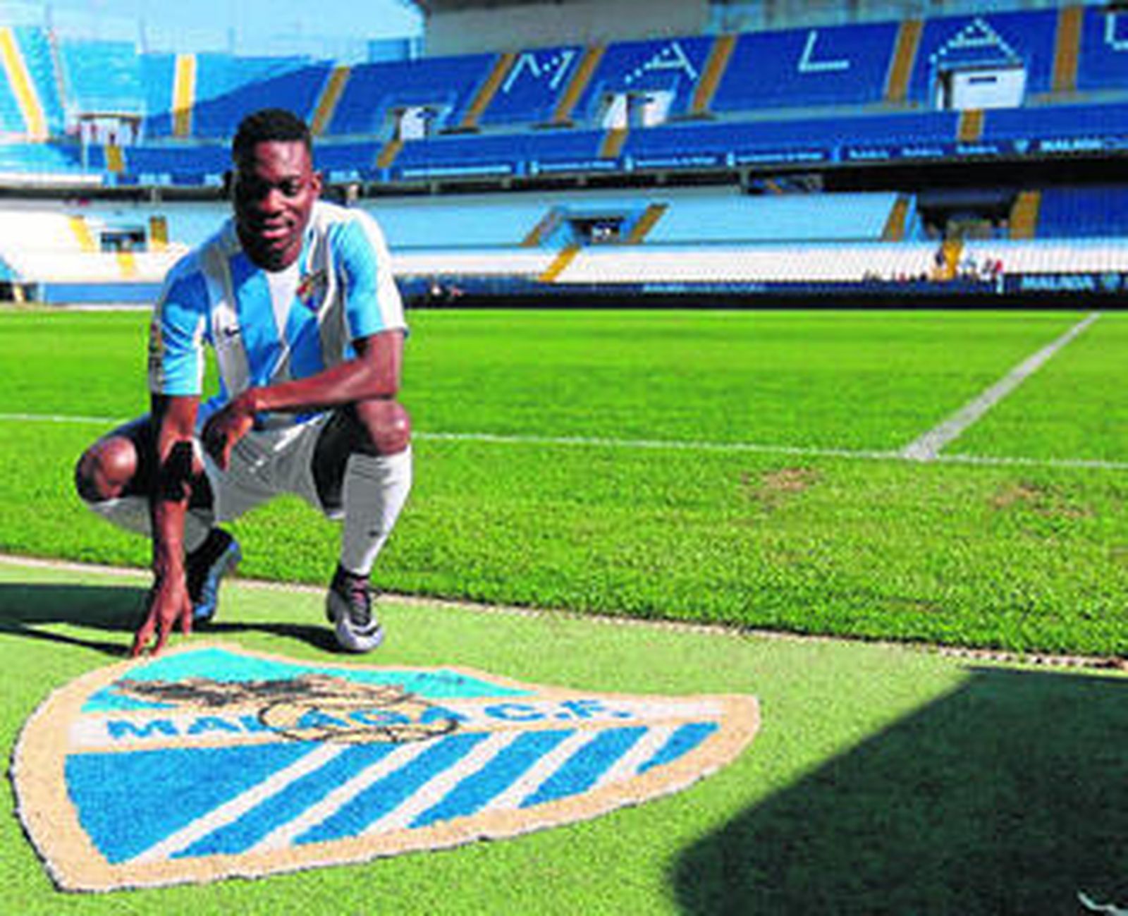 Christian Atsu posa sobre un escudo del Málaga en La Rosaleda el día de su presentación.