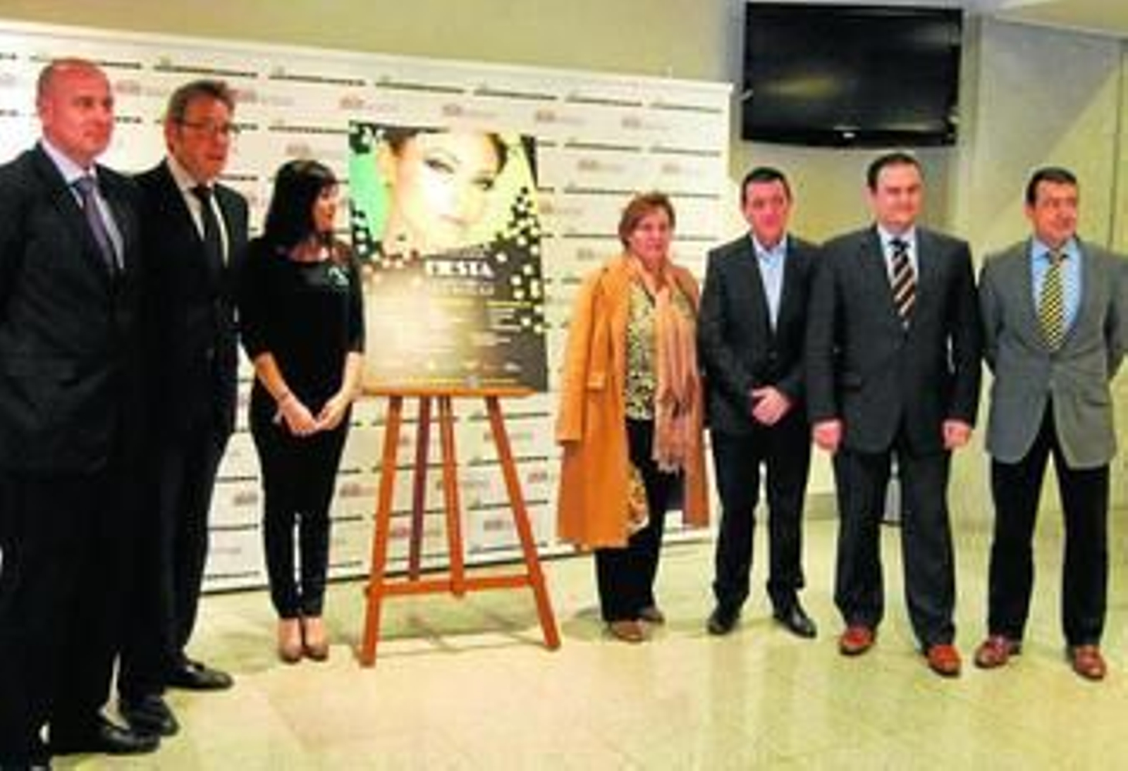 Representantes del Grupo Por... de El Pan Nuestro y la madre de Carlos Pita, junto al cartel de la pasarela.