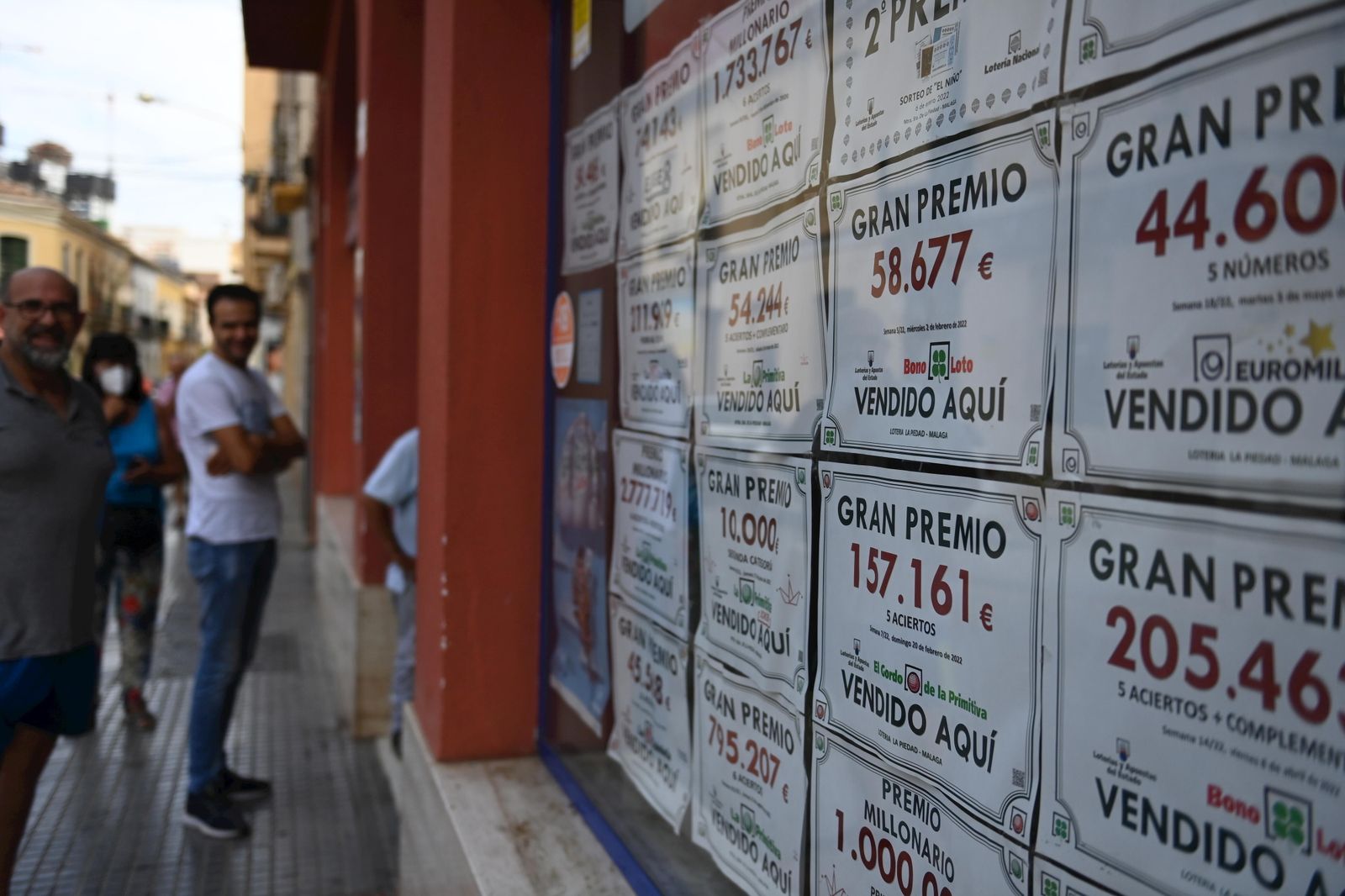 Varios carteles con décimos premiados en la fachada de una administración de lotería.