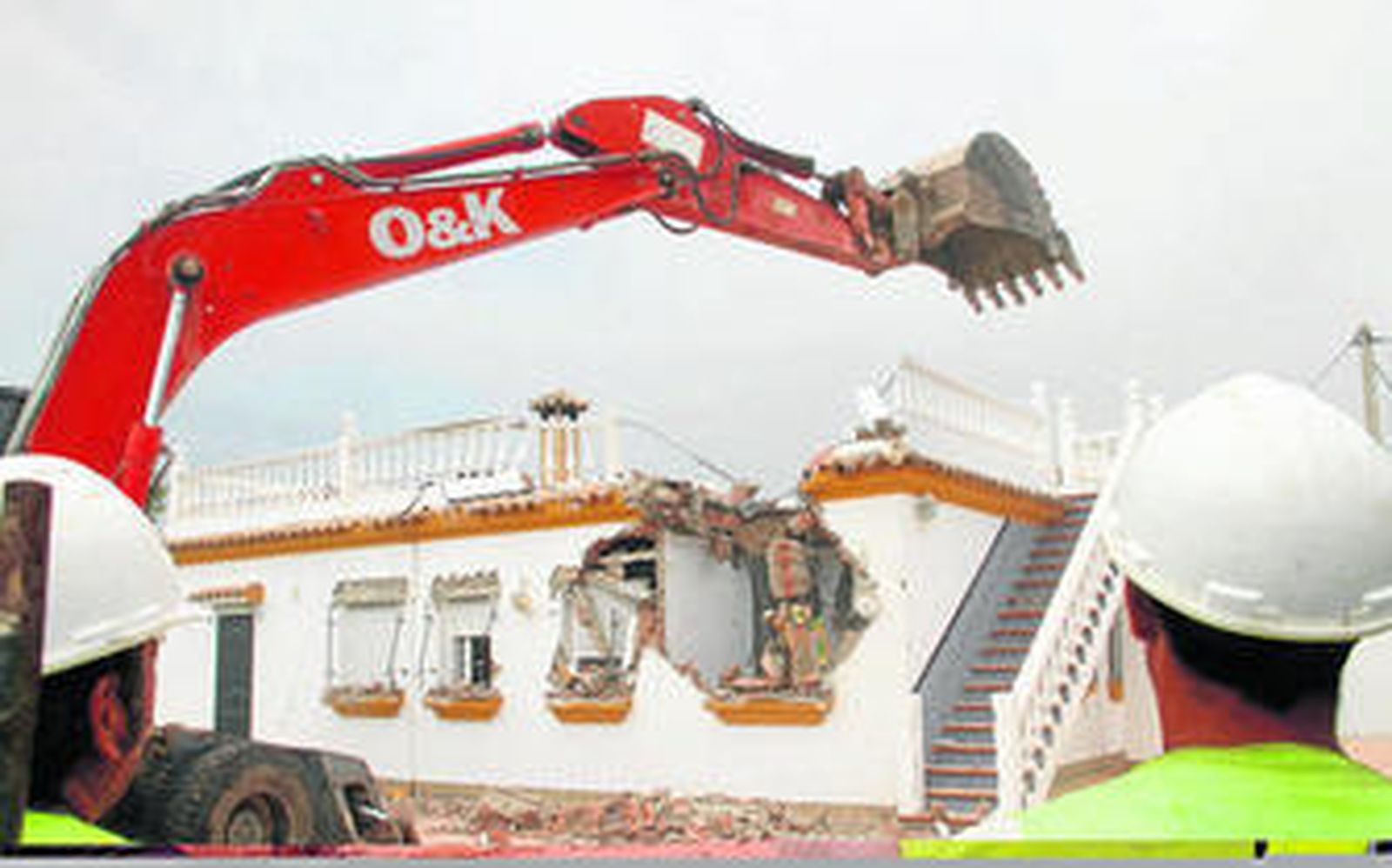 Dos operarios de la empresa de demoliciones visualizan el trabajo que efectúa la máquina retroexcavadora sobre la vivienda situada en El Palmar.