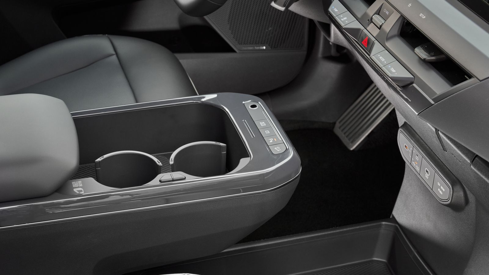 En el apoyabrazos central se sitúa la base de carga inalámbrica junto a los posavasos. Asimismo, se incluyen algunos mandos o el sensor de huella.