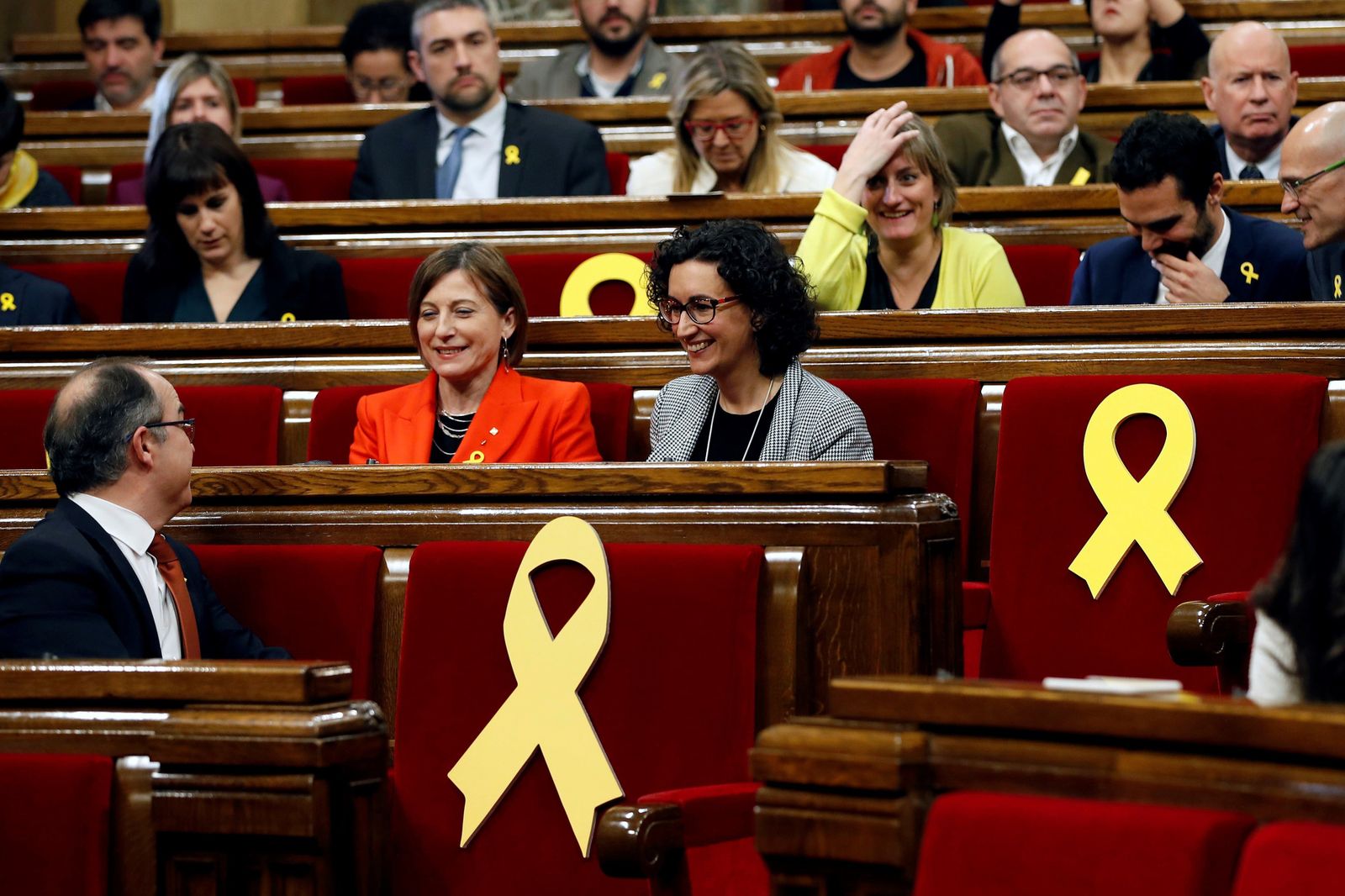 La presidenta del Parlament, Carmen Forcadell (i), y la secretaria general de ERC, Marta Rovira (d), rodeadas por varios escaños vacios adornados con lazos amarillos en recuerdo de los diputados electos encarcelados y huidos.