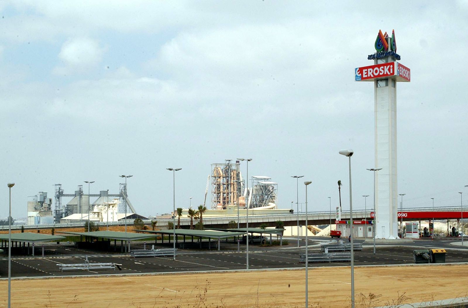 El aparcamiento del centro comercial, con la torre en la que se anuncia monolito en el que se anuncia Eroski y su gasolinera.