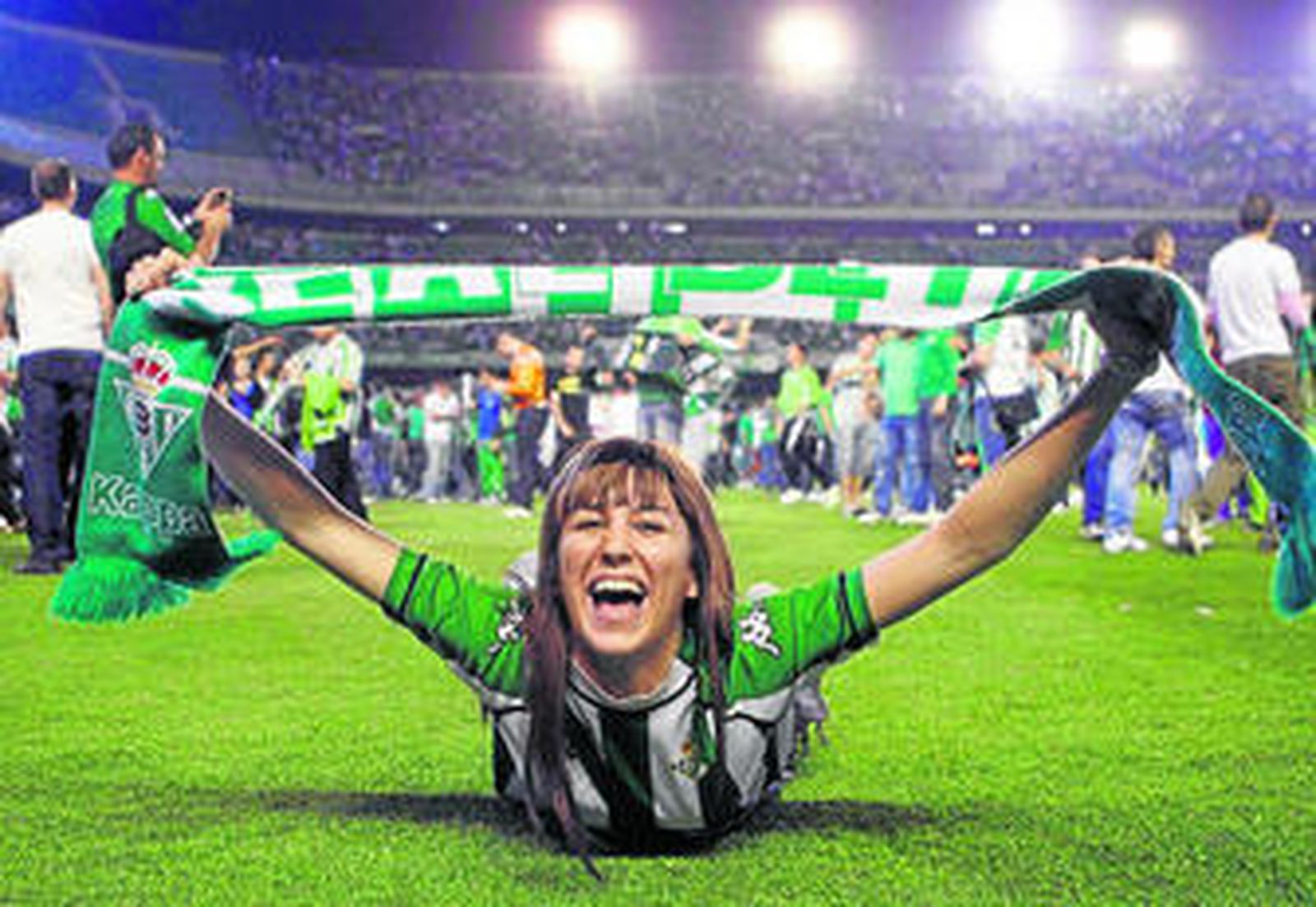 Una aficionada verdiblanca celebra el triunfo sobre el césped del estadio bético.