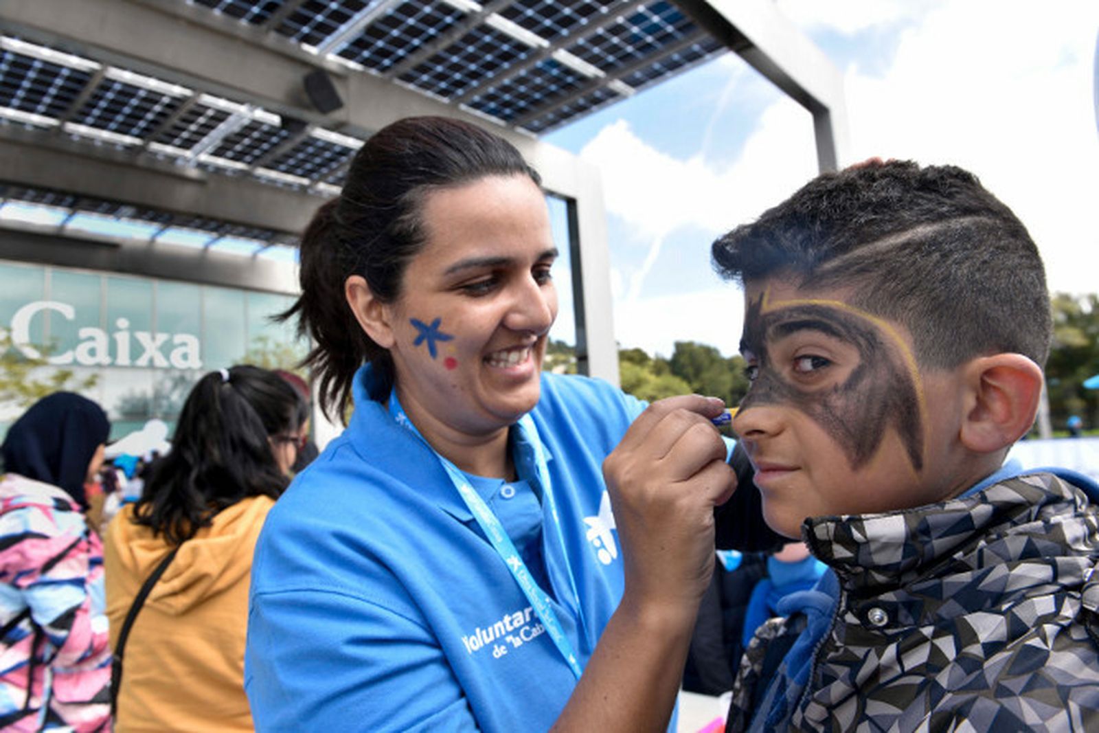 Una animadora pinta la cara a un niño.