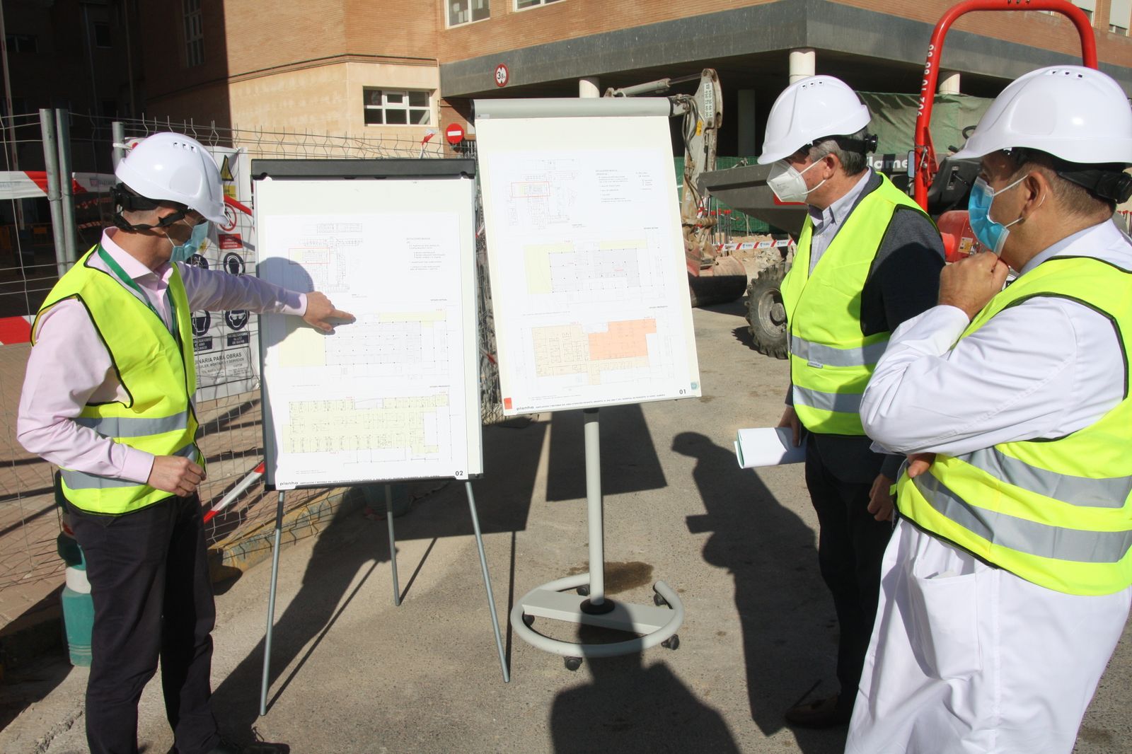 El delegado de Salud y el gerente de la agencia Poniente atienden las explicaciones de Ramón Estrada.