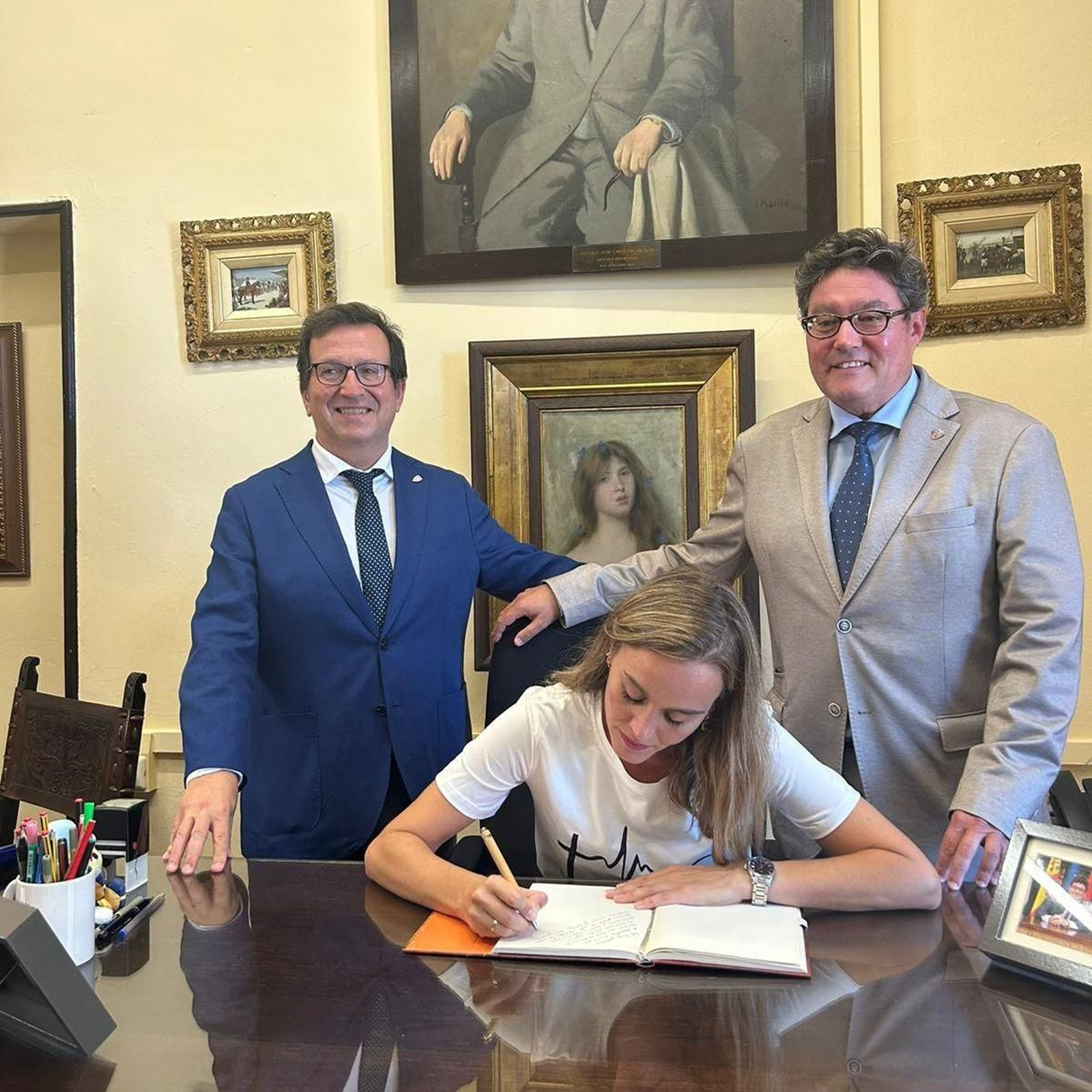 Maria Espejo, firmando en el libro de honor junto a Moisés García, director, y José Ángel Aparicio.
