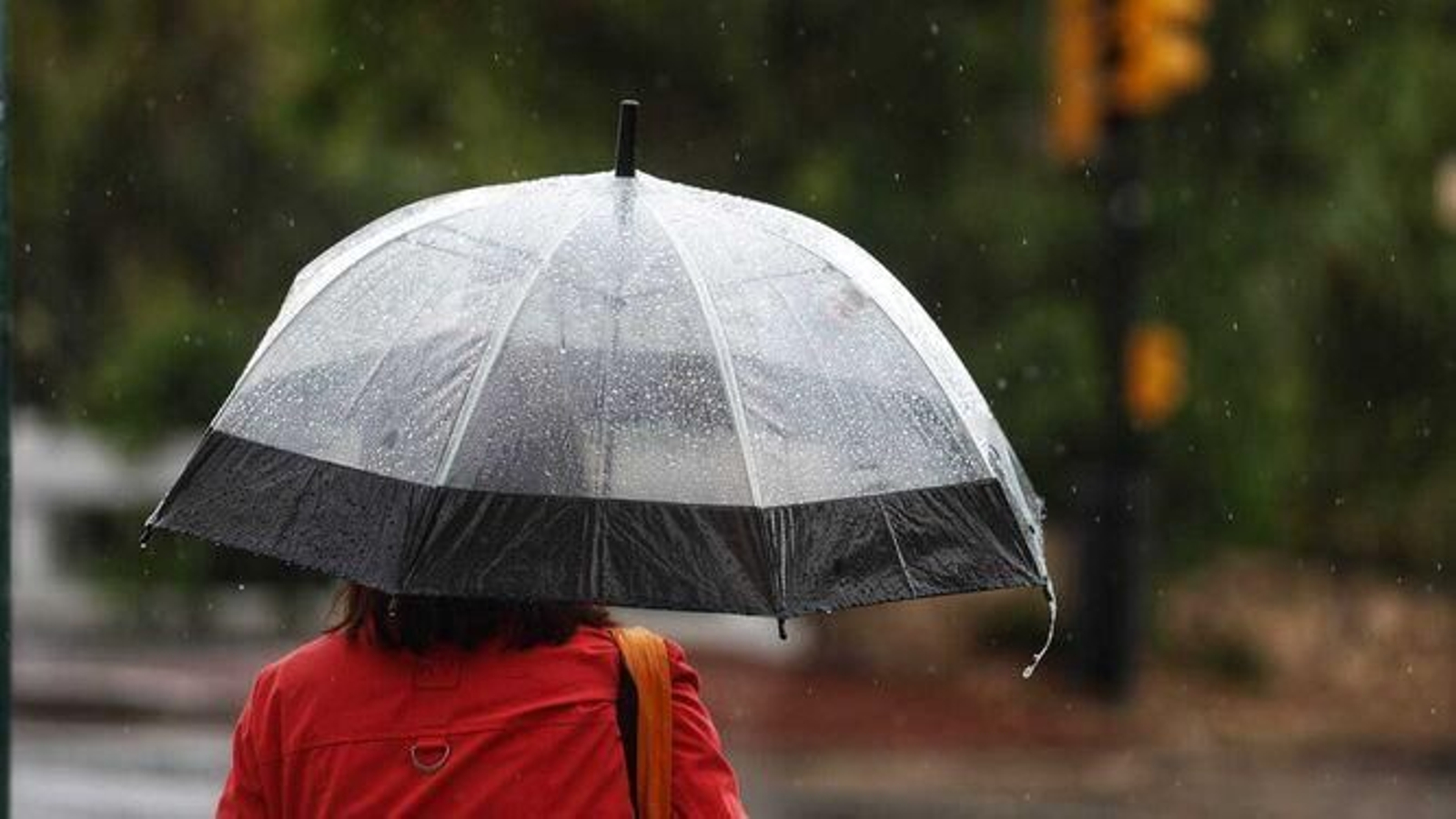 Una mujer protegiéndose de la lluvia con un paraguas Una mujer protegiéndose de la lluvia con un paraguas