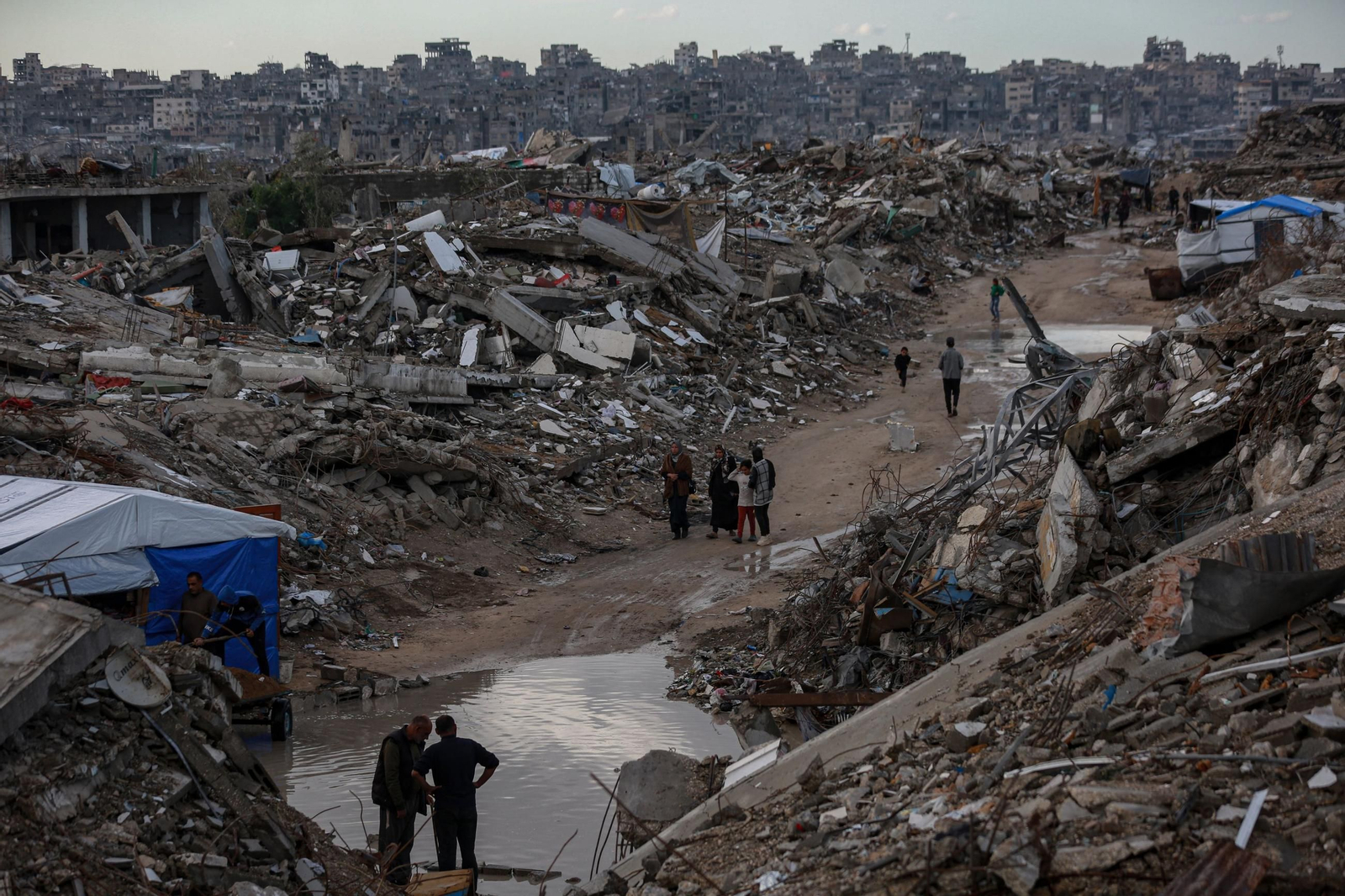 Palestinos caminan entre la destrucción y los charcos en el campamento de Jabalia.
