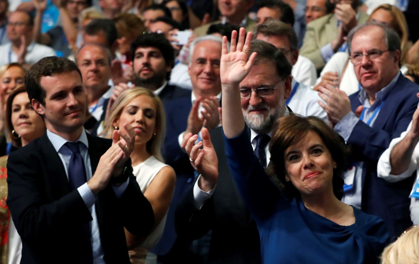 Soraya Sáenz de Santamaría saluda a los asistentes al congreso del PP mientras Pablo Casado y Mariano Rajoy la aplauden.