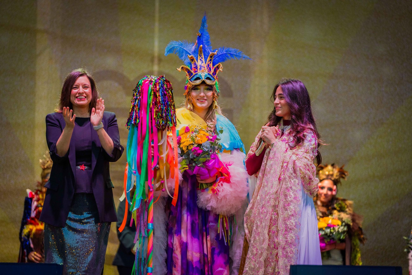 Julia Pascual Martín, como Colombina Mayor representa con su disfraz al Carnaval. Predominan en el traje el color y elementos tan carnavaleros como la serpentina, los papelillos o la purpurina