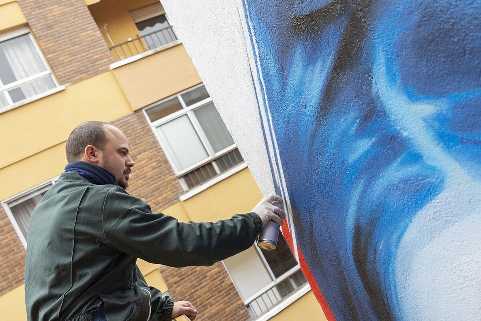El artista onubense Manomatic, en acción, en el mural distinguido.