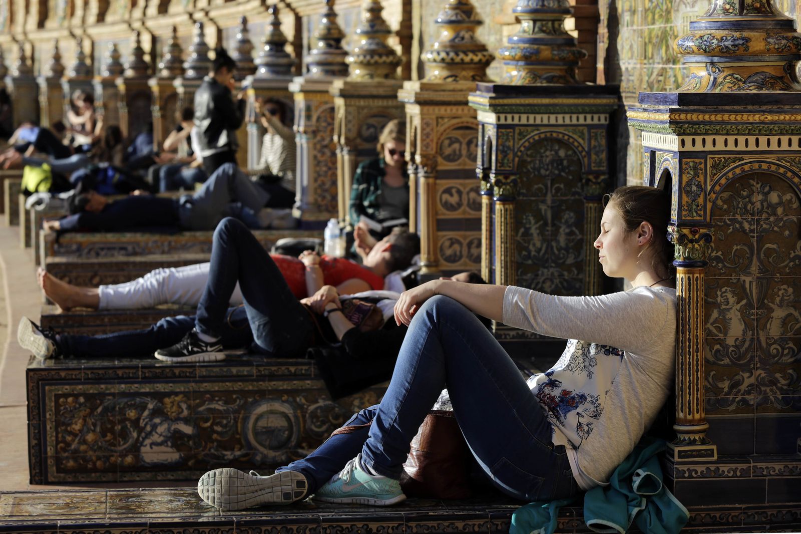 Jóvenes disfrutan al sol en la Plaza de España.