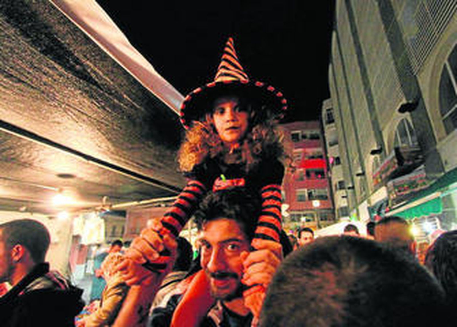 Una pequeña con disfraz a hombros de su padre, anoche en el mercado de abastos.