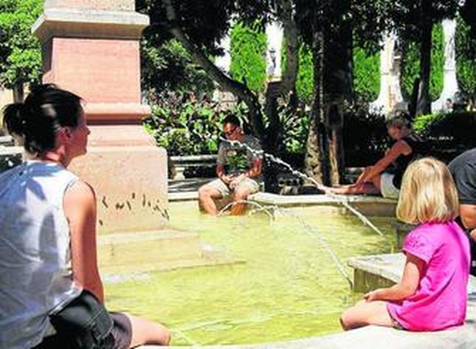 Varias personas se refrescan en una fuente de Ronda.