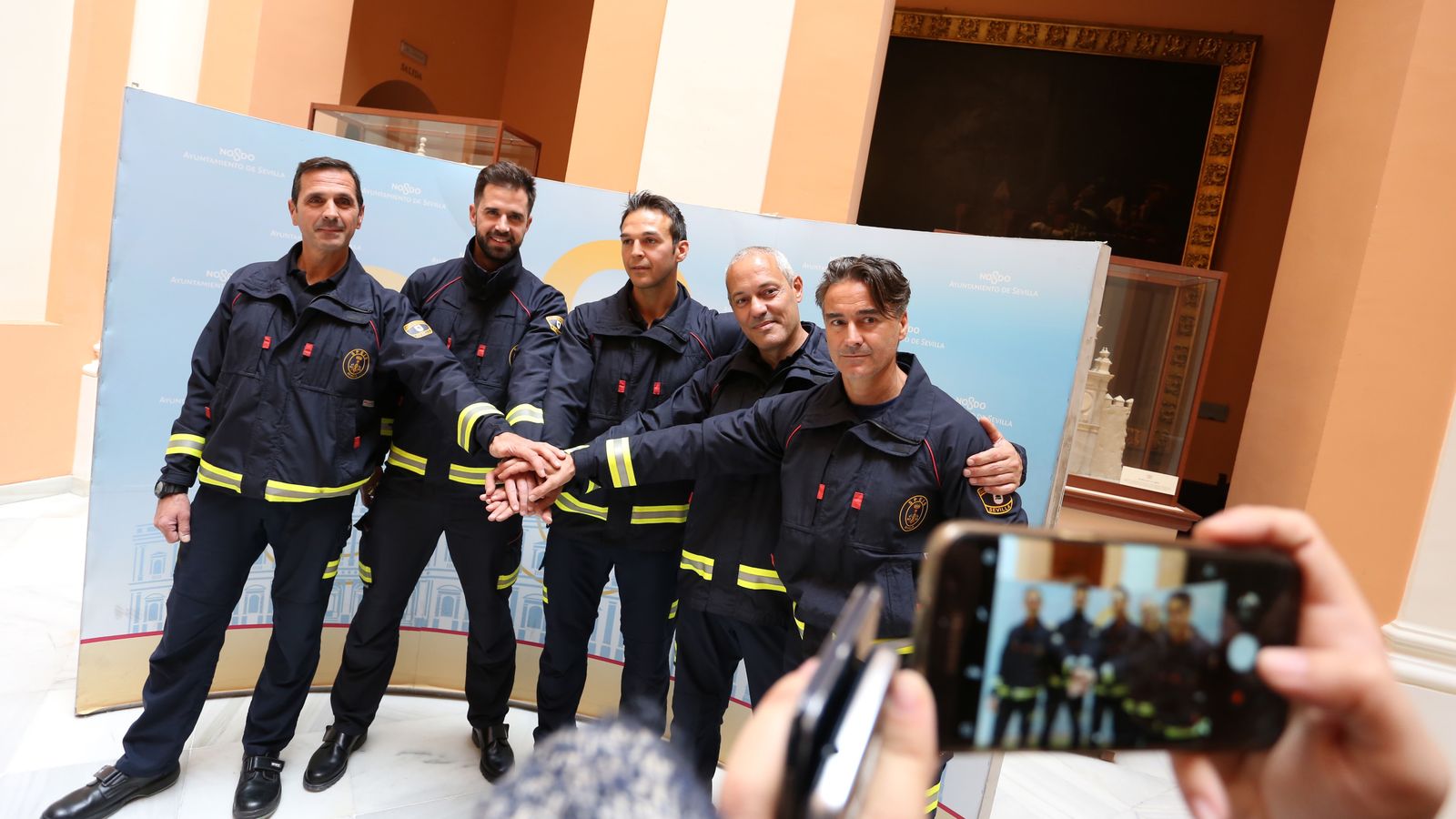 Piña de los bomberos en el Consistorio. En el centro, los tres protagonistas del rescate.